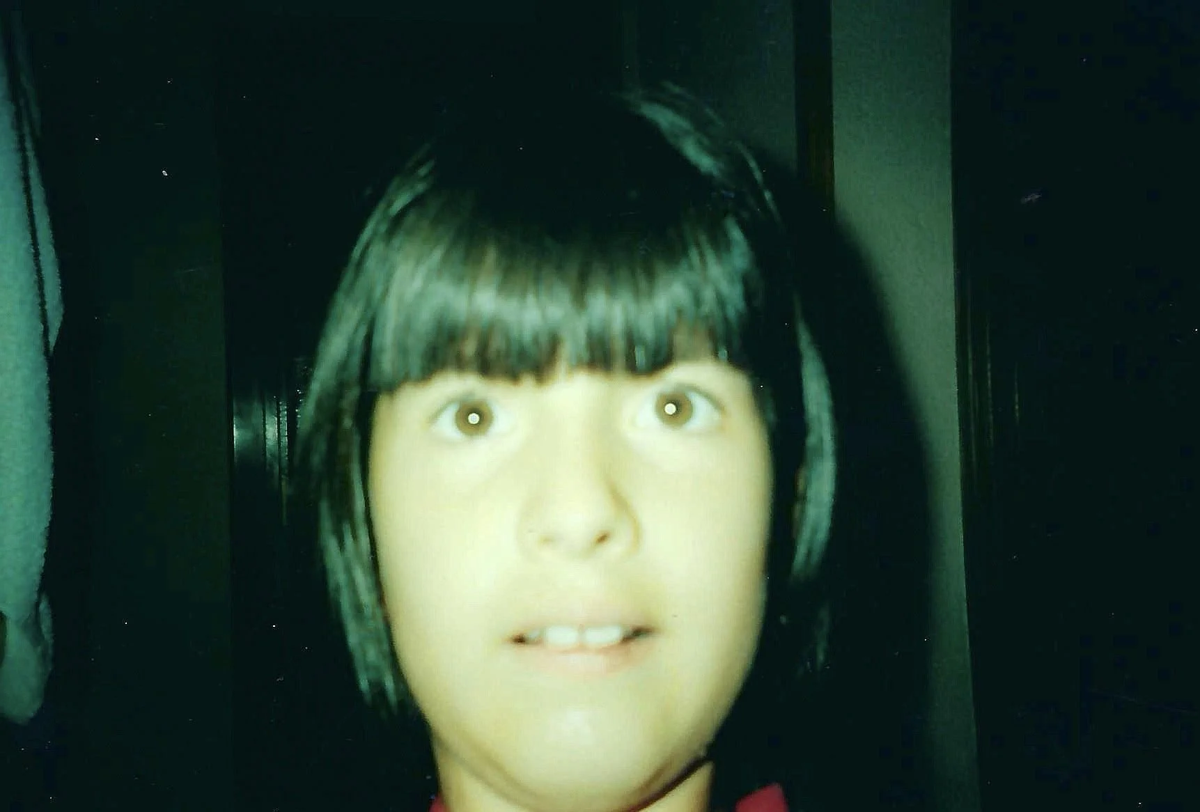 A mannequin head with short dark hair, light skin tone, and wide eyes, positioned in front of a dark background.