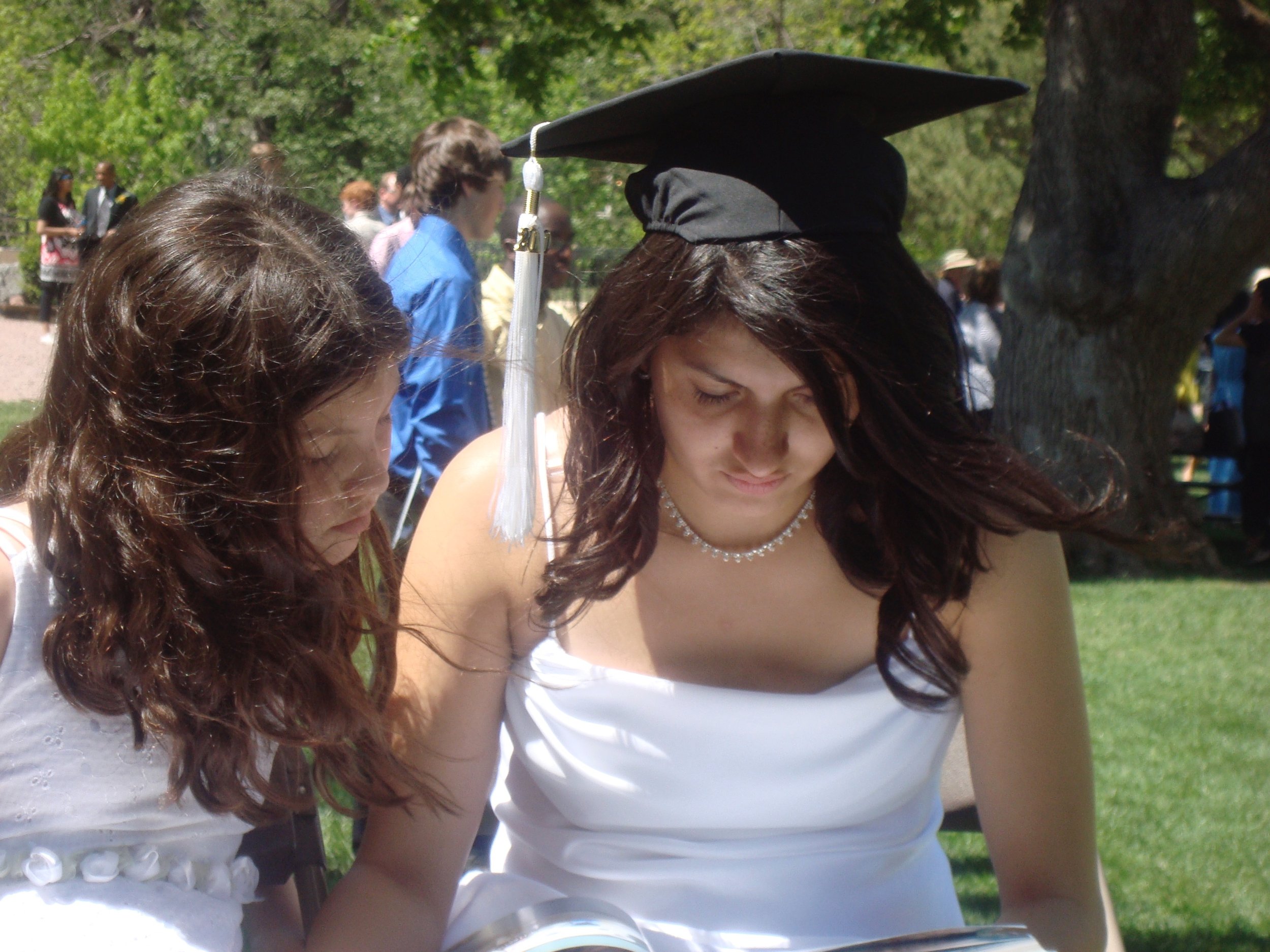 A woman wearing a graduation cap and gown at an outdoor graduation ceremony.