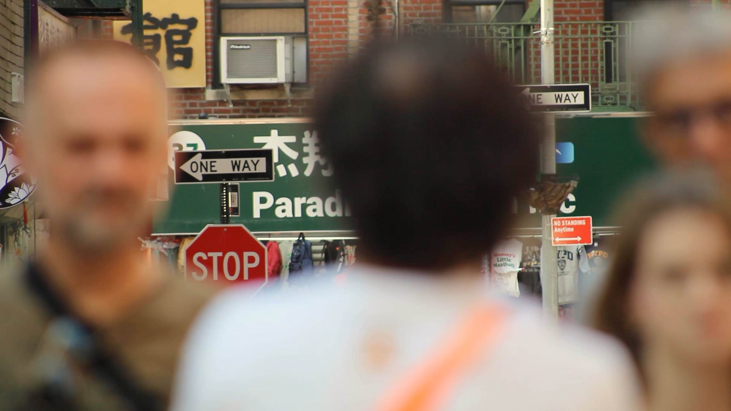 An image of a stop sign in Chinatown framed by strangers passing by..