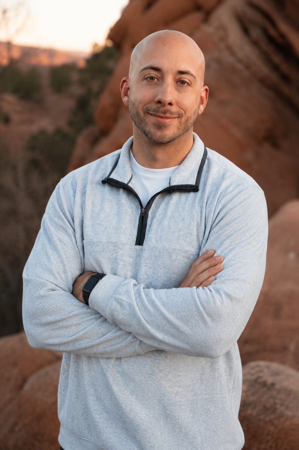 man wearing gray zip up smiling in front of rocks