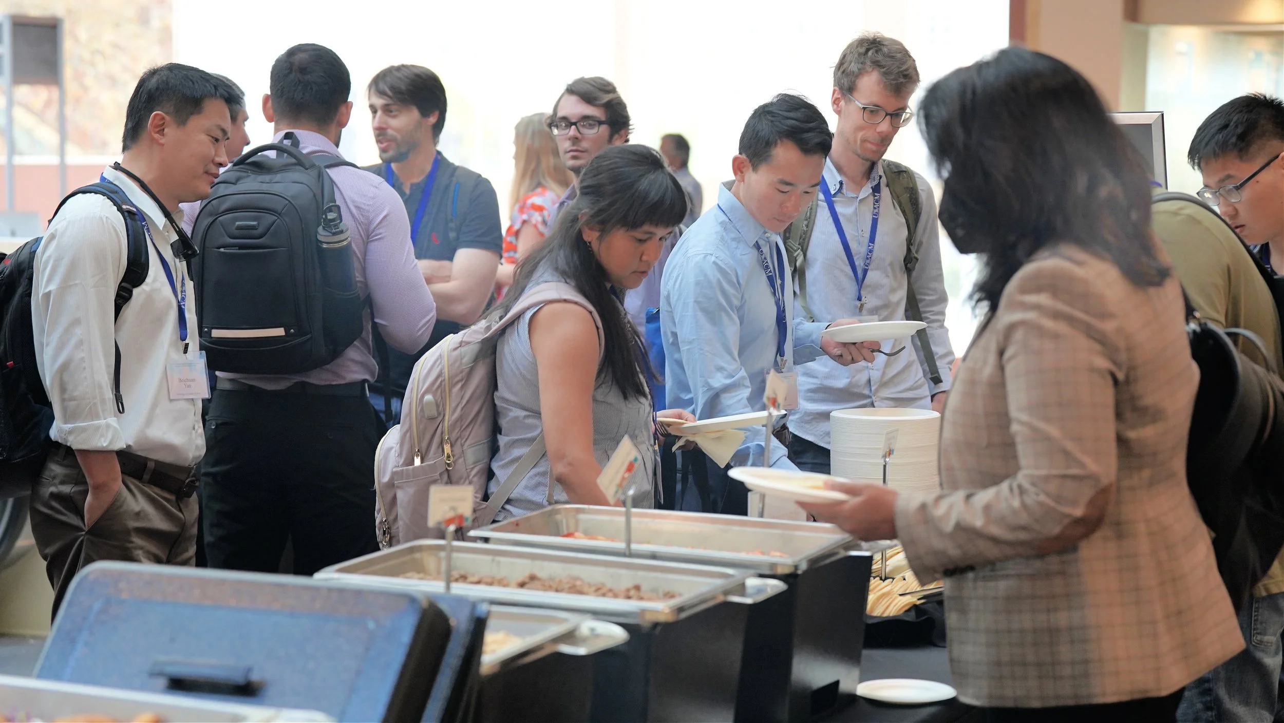 People in line at a buffet table, serving themselves food at a conference or event.