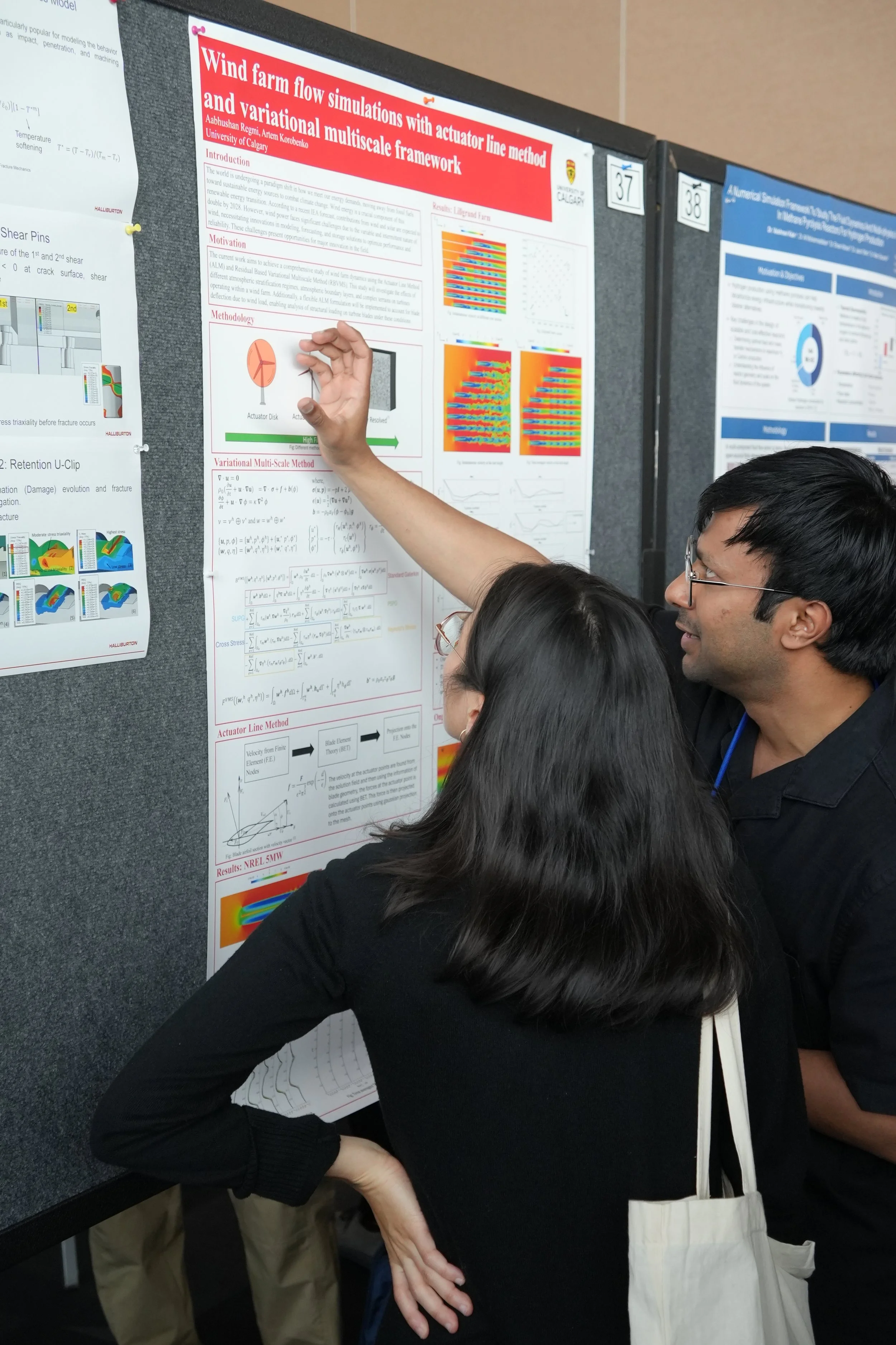 People discussing scientific research posters at a conference, focusing on a poster about wind farm flow simulations with actuator line method.