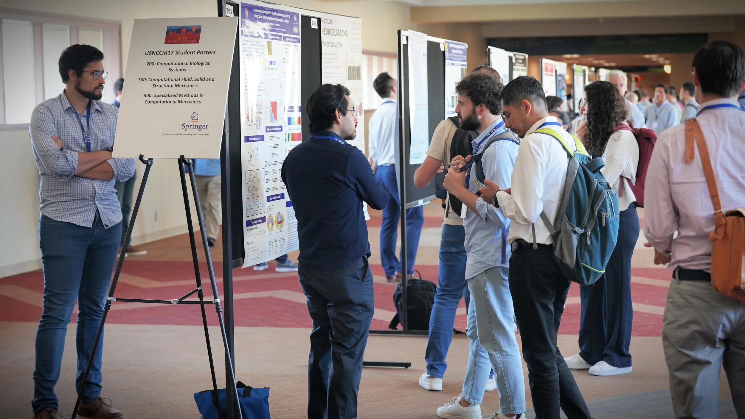 People attending a scientific conference, viewing research posters in a large hallway.