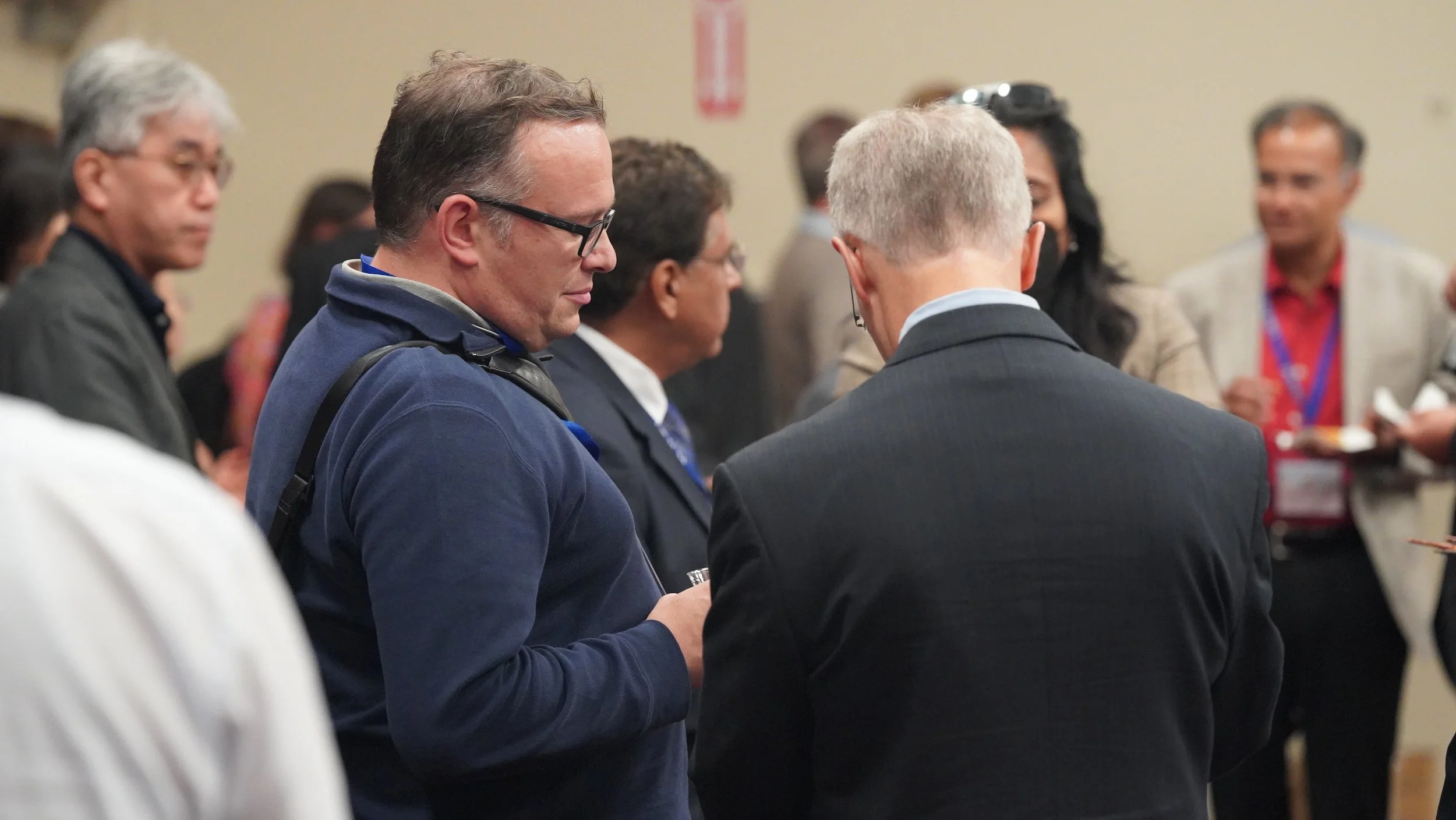 Group of professional people at a conference or networking event, engaged in conversation and networking.