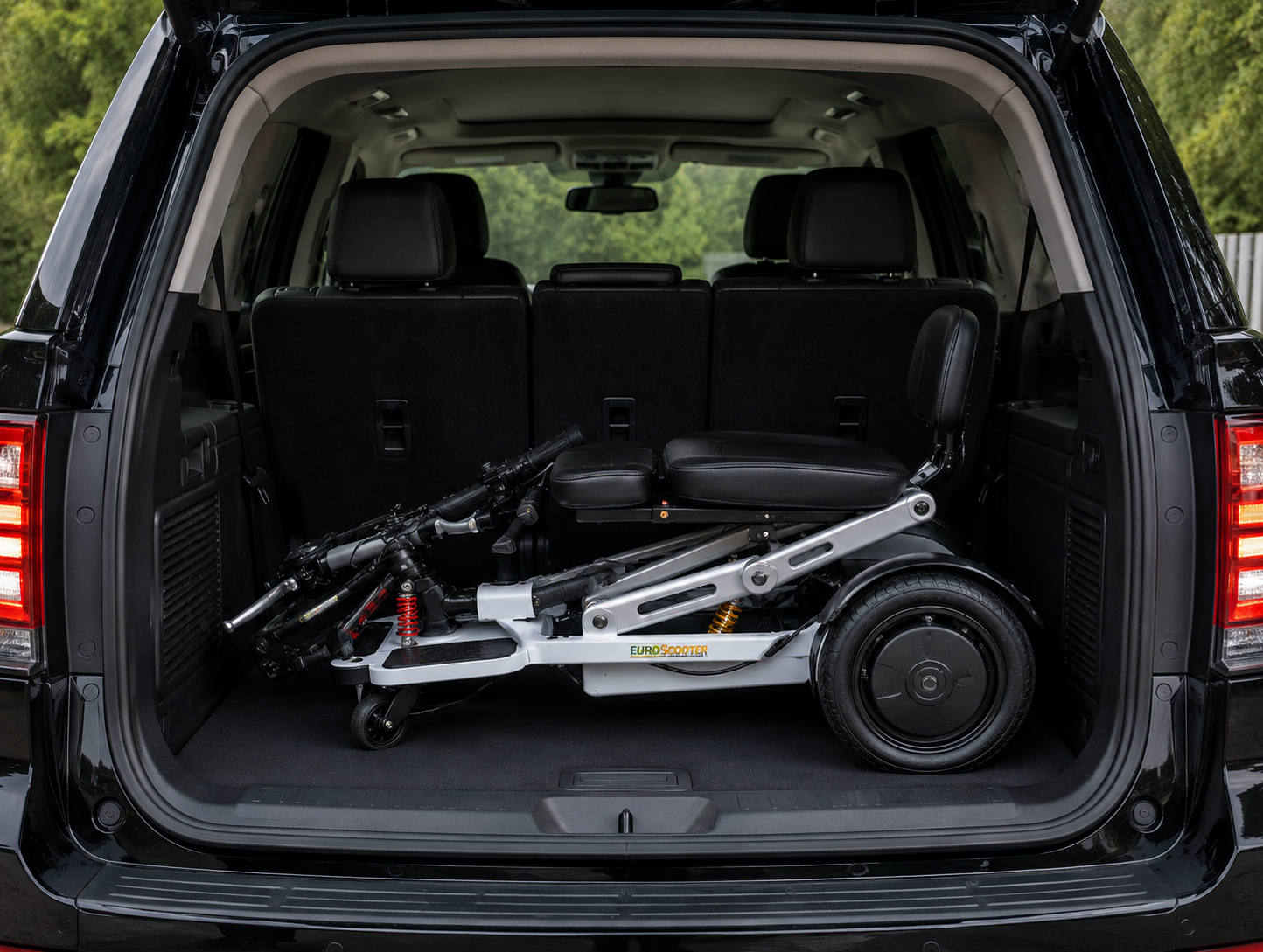 The open trunk of a black SUV with a small electric scooter inside, showing its black seat, wheels, and silver frame.