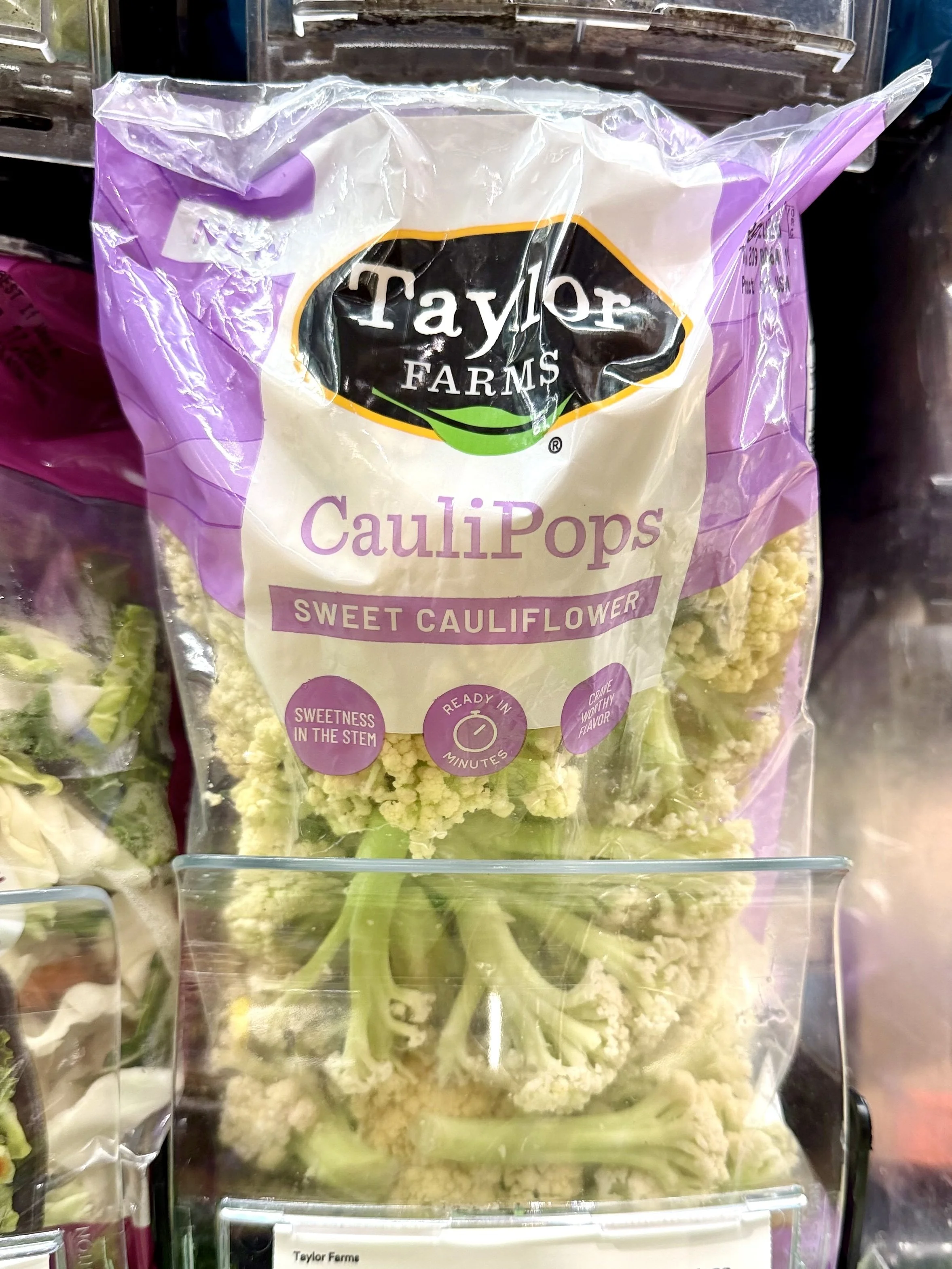 A clear plastic bag of Taylor Farms sweet cauliflower called CauliPops on store shelf.