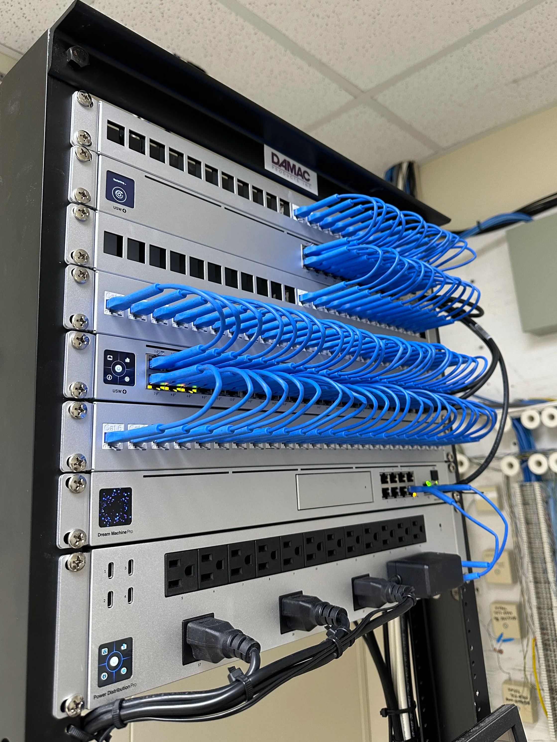 Close-up of a data server rack with multiple Ethernet cables connected and displaying network activity lights.