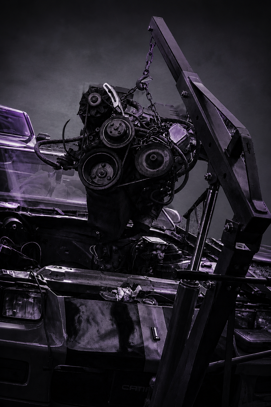A car being repaired with its engine hoisted by a crane, parts and tools visible in a dark environment.