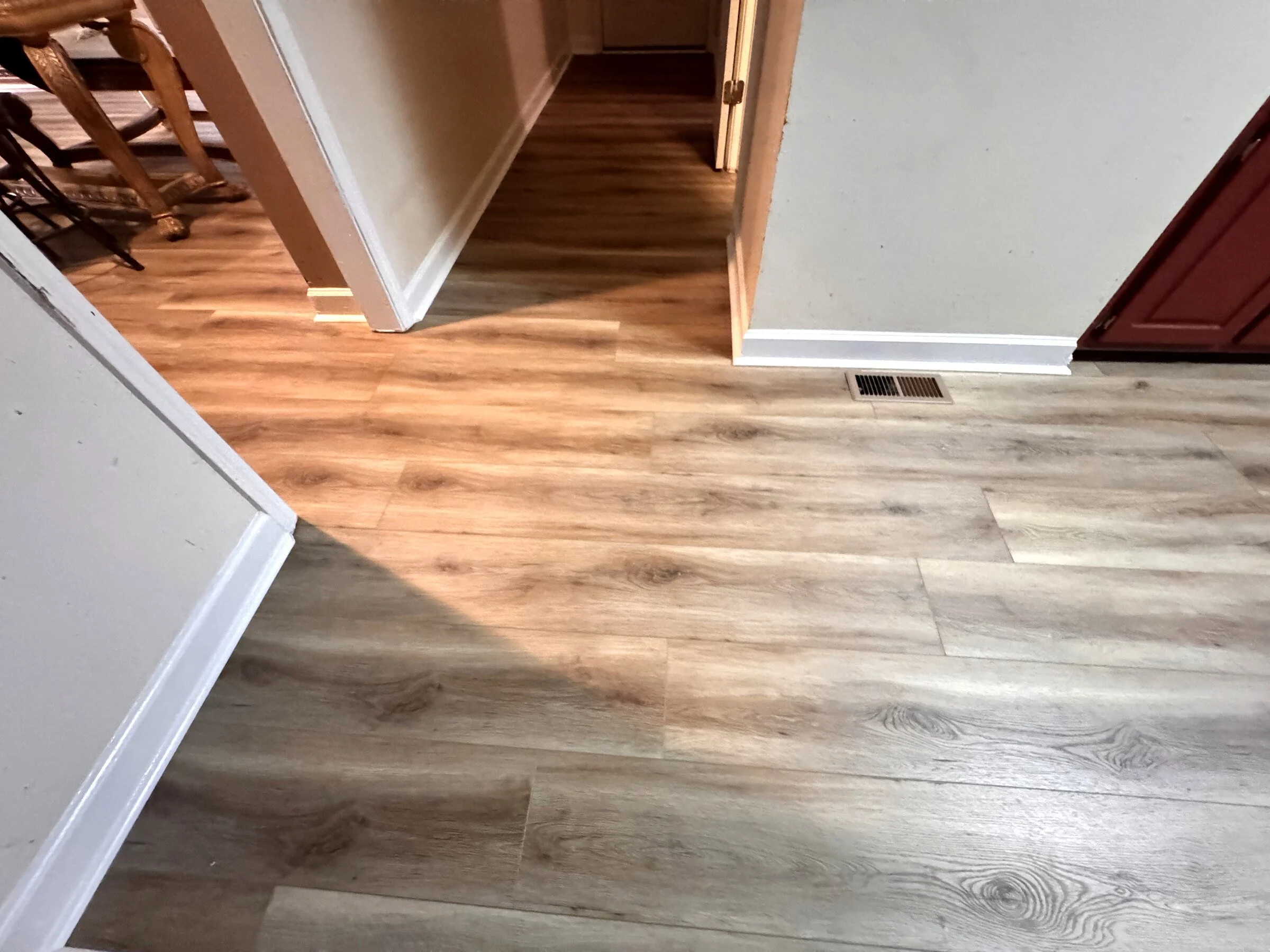 Finished gray luxury vinyl plank flooring connecting a kitchen and hallway in an Atlanta-area home