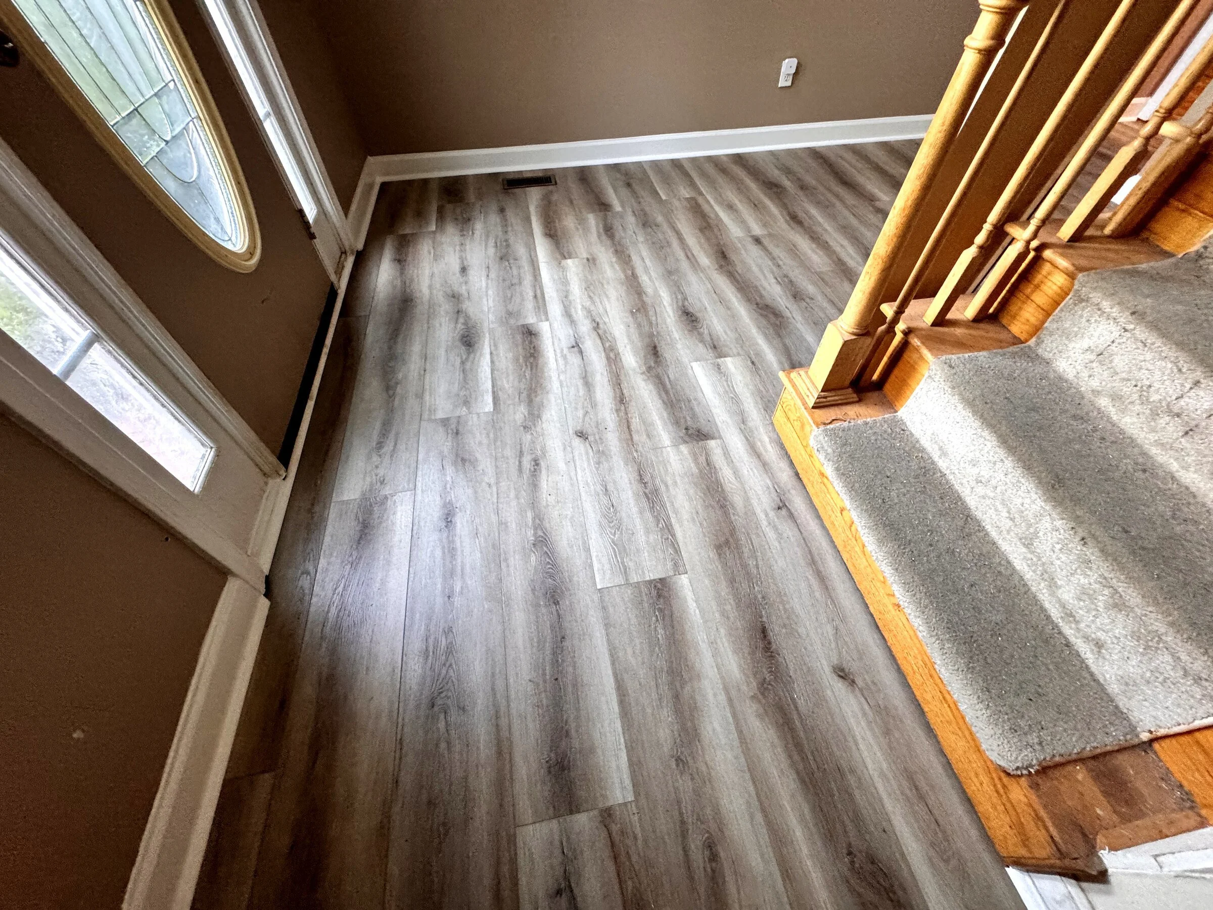 Finished gray luxury vinyl plank flooring beside a staircase in an Atlanta-area home