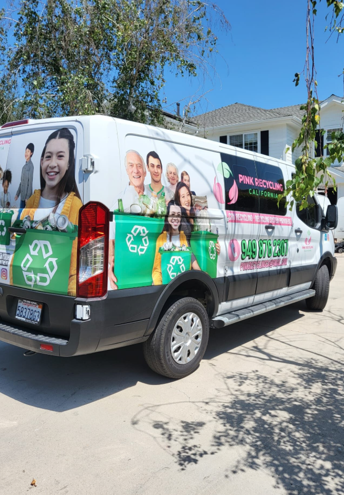Recycling truck with images of smiling people and pink and green graphics advertising Pink Recycling California, including a phone number 949-875-2837.