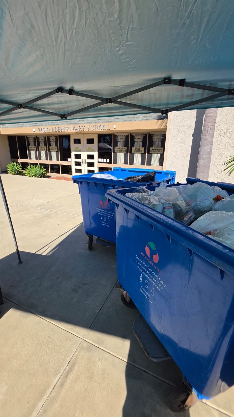 Trash bins with recycling bags in front of Viejo Elementary School.