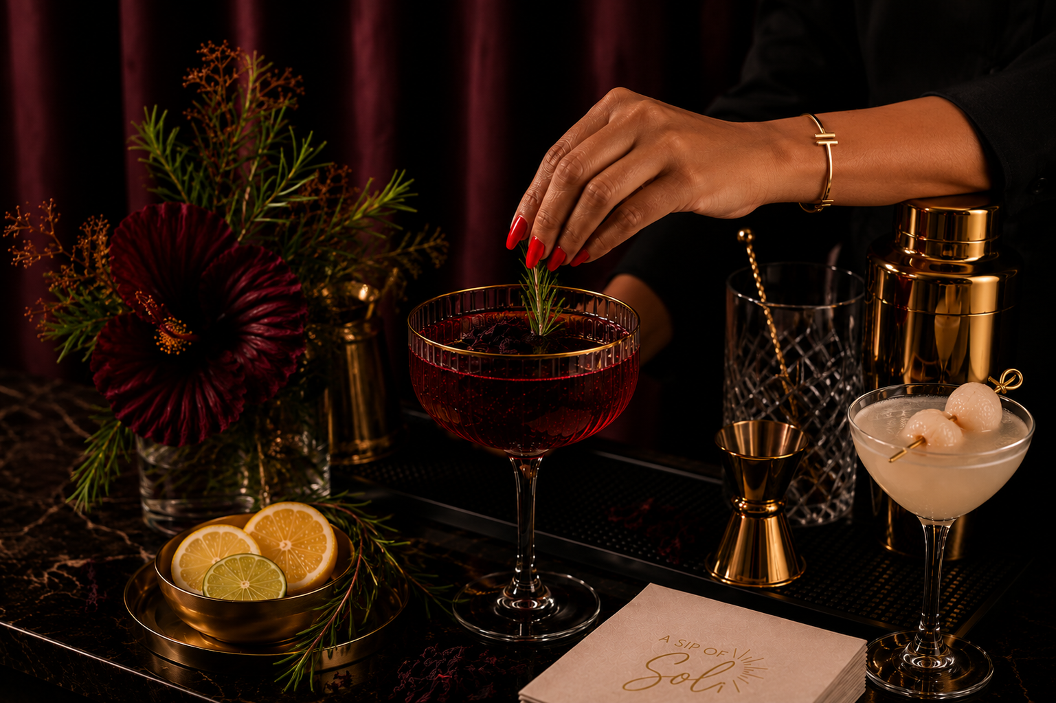 Bartender garnishing an elegant cocktail beside fresh citrus, a lychee martini and polished gold bar tools.