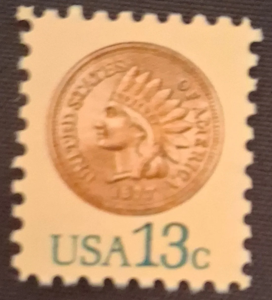 A U.S. postage stamp with a denomination of 13 cents, featuring an image of a Native American headdress and the words 'USA 13c' at the bottom.