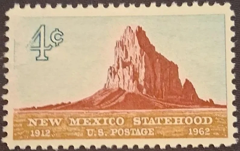 A Mexican postage stamp featuring the landscape of a prominent rock formation or mountain with 4 cents denomination, issued in 1962, commemorating the 50th anniversary of New Mexico statehood, with the text "New Mexico Statehood 1912 - 1962."