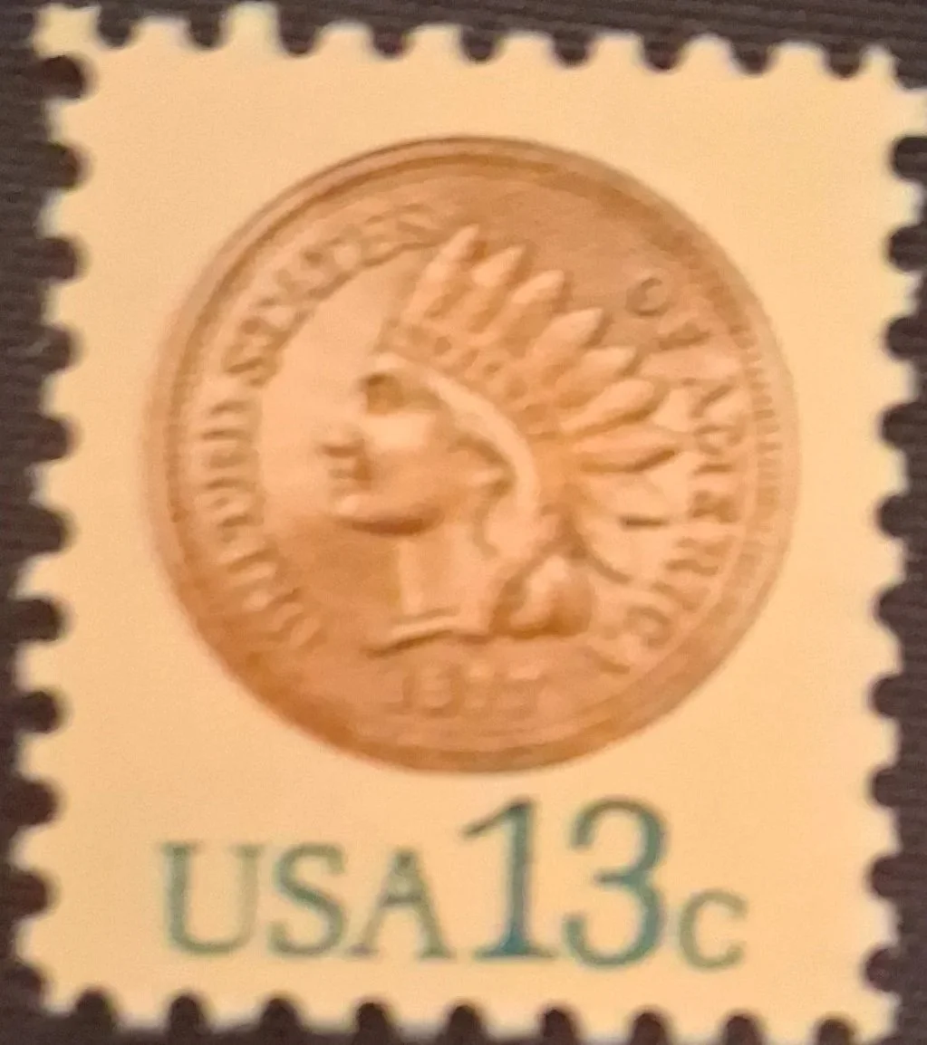 Close-up of a U.S. postage stamp featuring a Native American head wearing a feathered headdress with the denomination 13 cents.