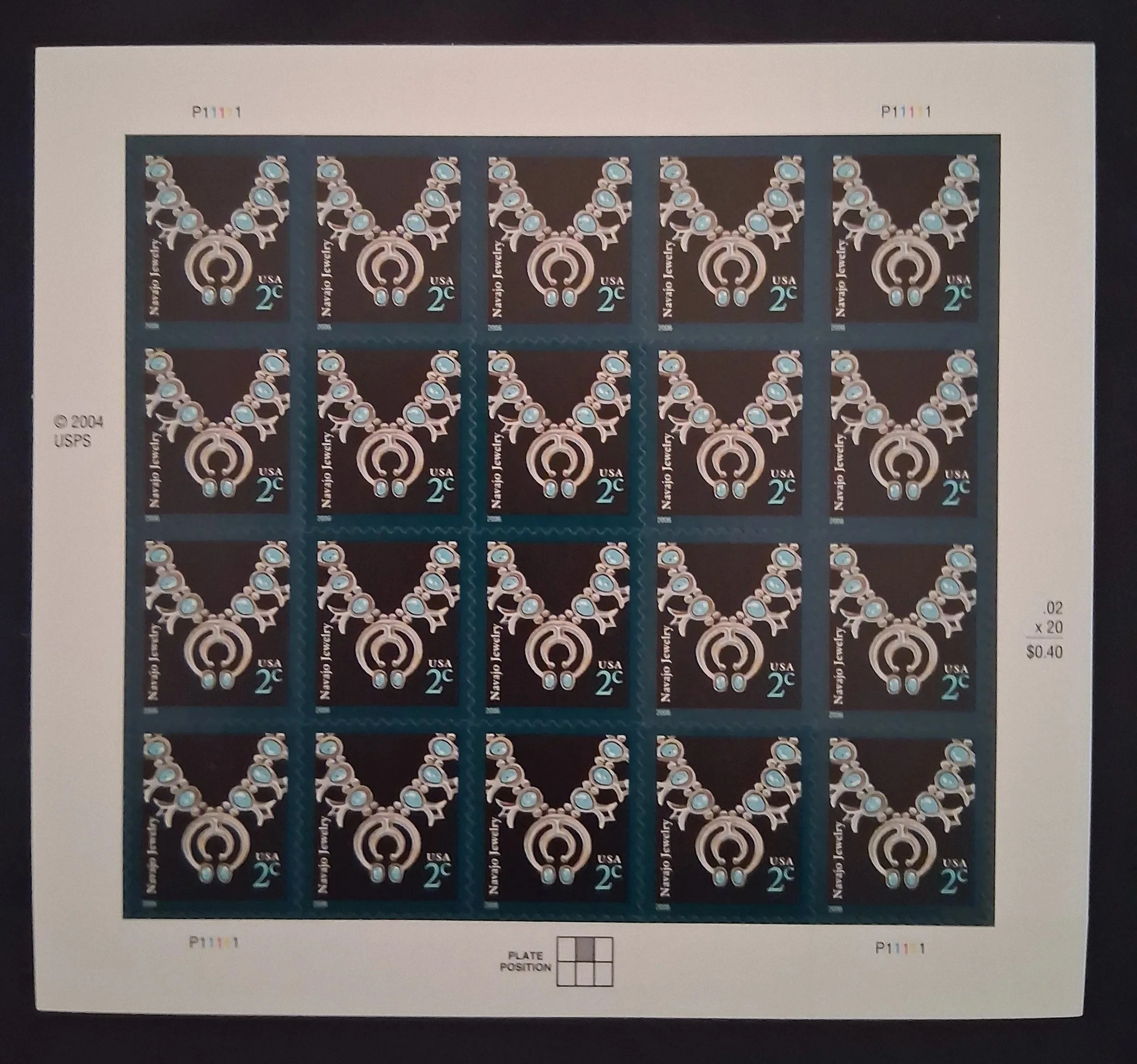 Sheet of U.S. postage stamps featuring a jewelry design with blue gemstones and intricate gold detailing, marked as 2 cents each.