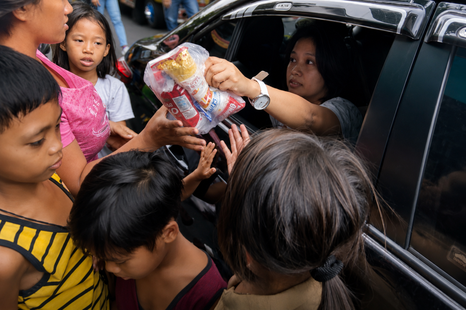 Sandielyn Taylor in a car hands a bag of snacks to a group of children gathered outside.