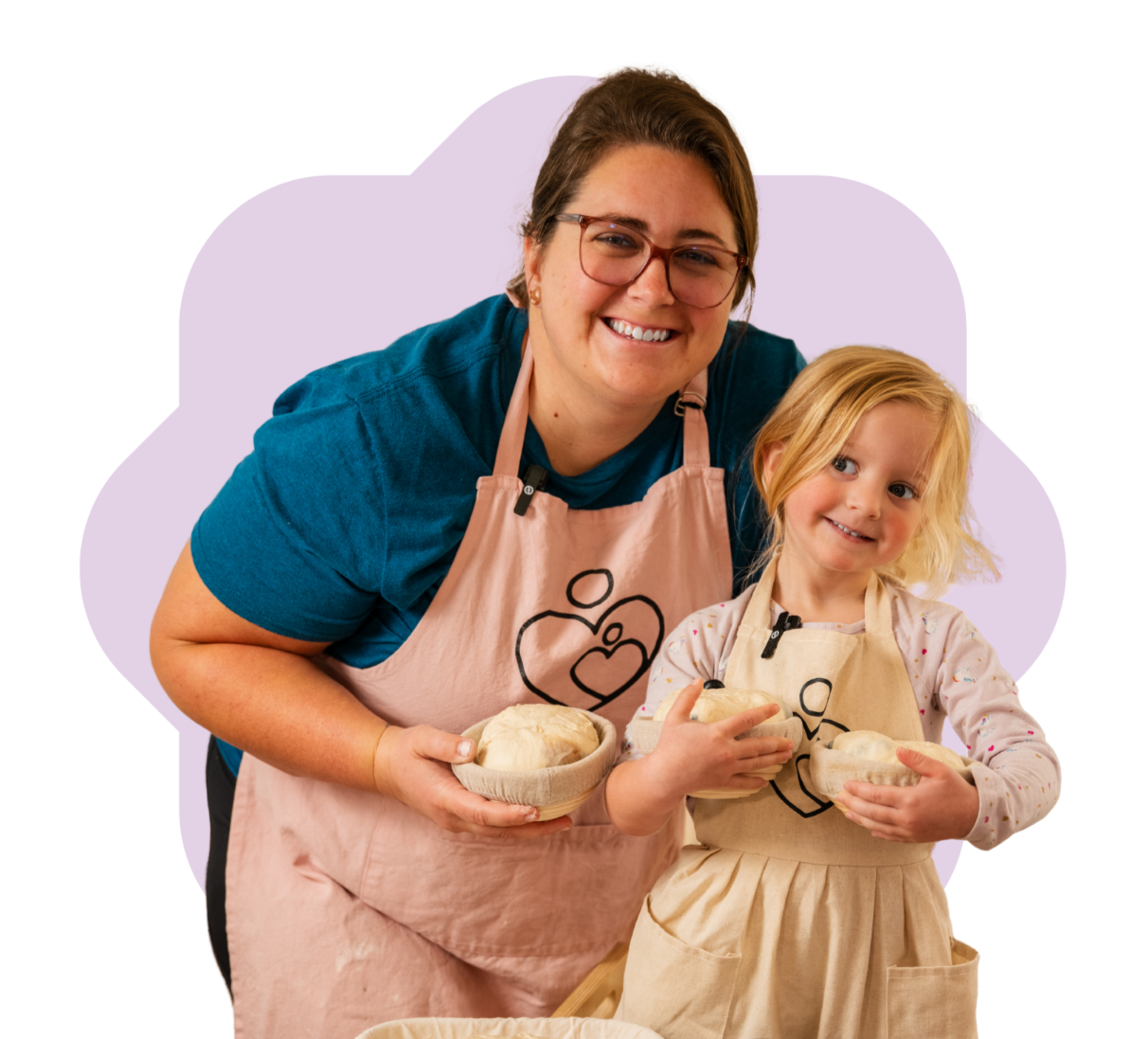 A woman and young girl smile while holding dough during a baking activity.