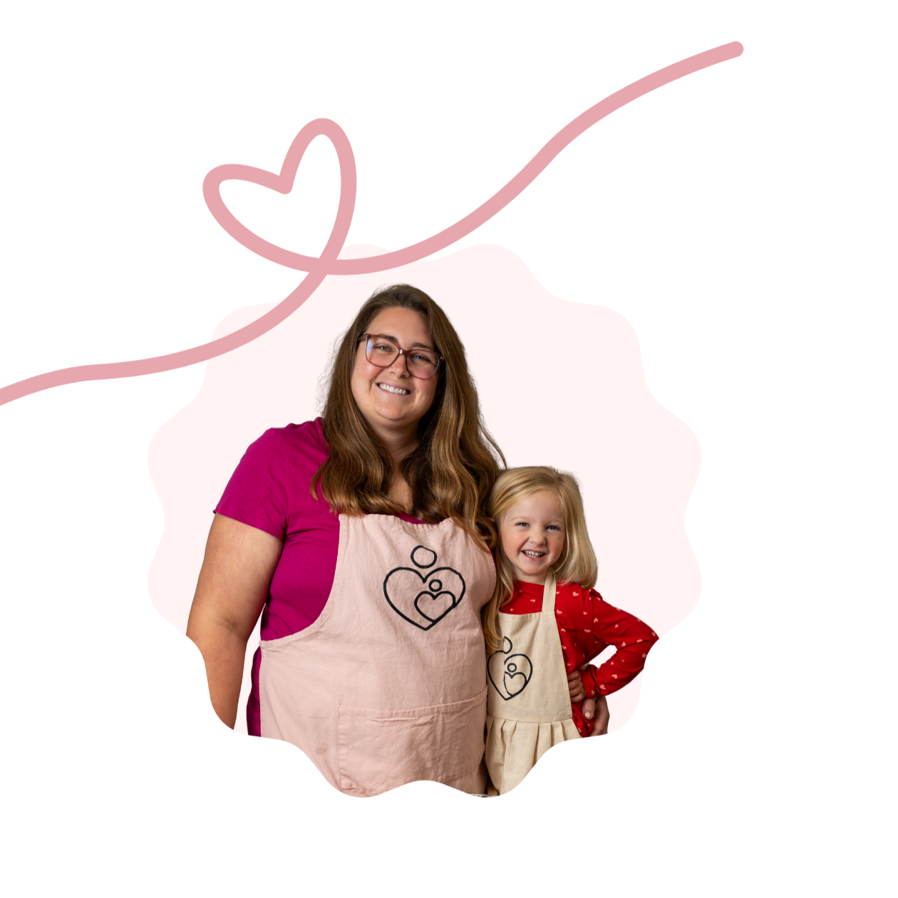 A woman and young girl wear matching heart-print aprons for a baking activity.