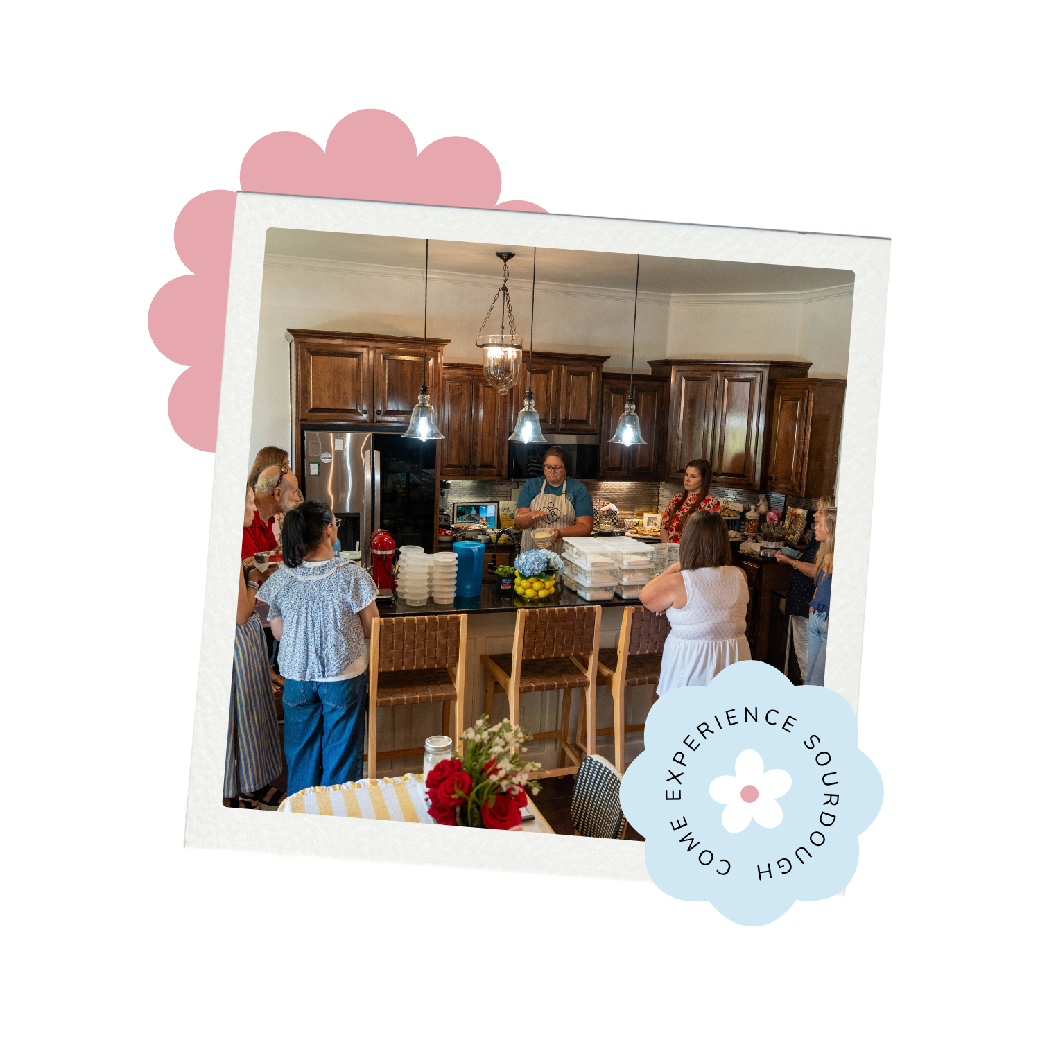 A woman demonstrates a baking technique to a group gathered around a kitchen island.