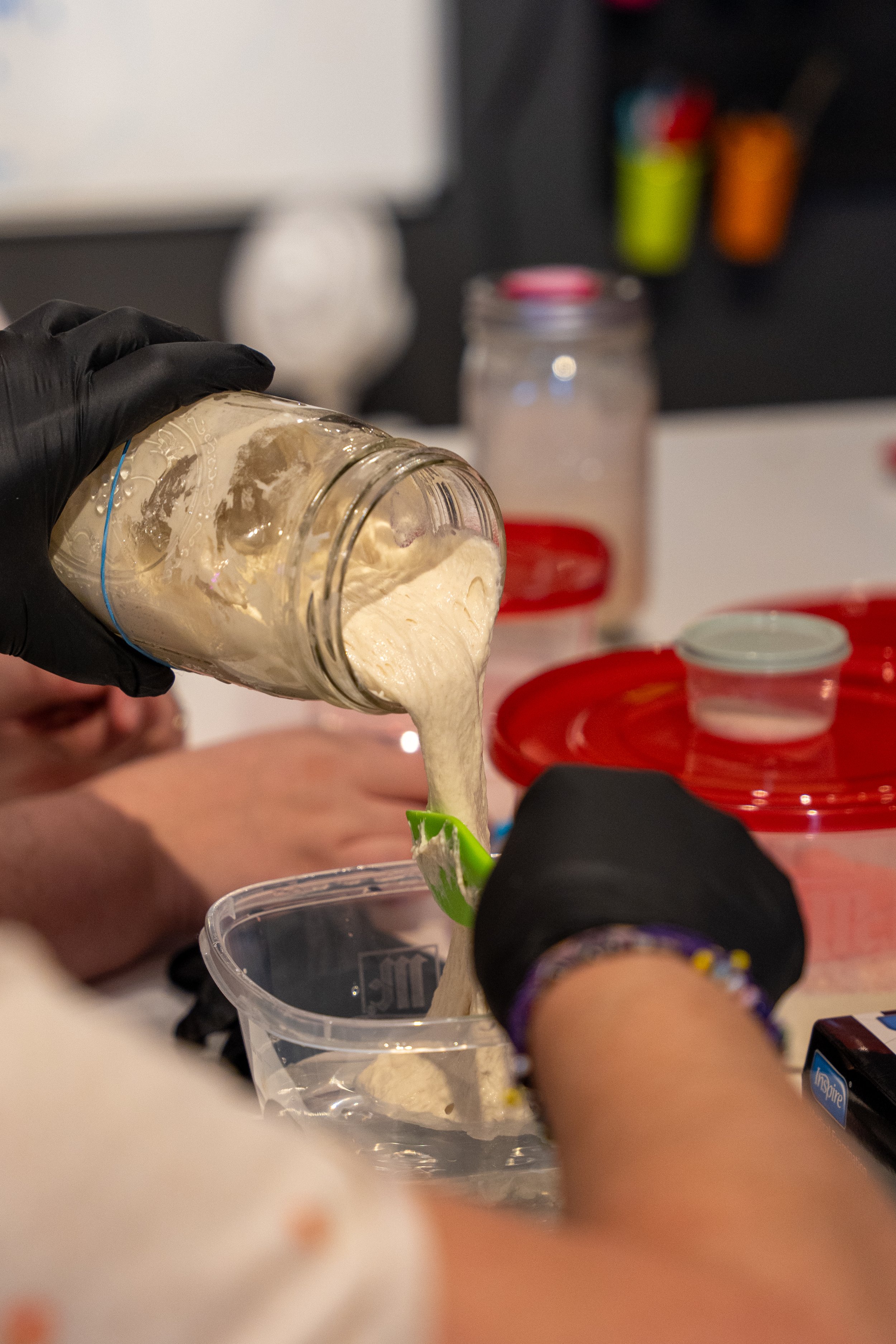 A person pours sourdough starter from a glass jar into a bowl.