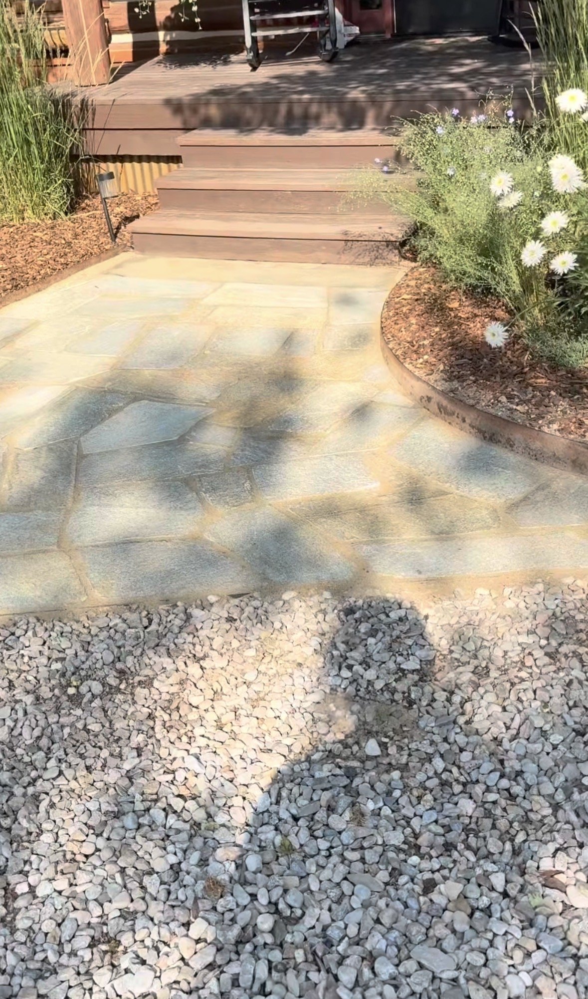 A flagstone walkway leading up to a wooden deck. 