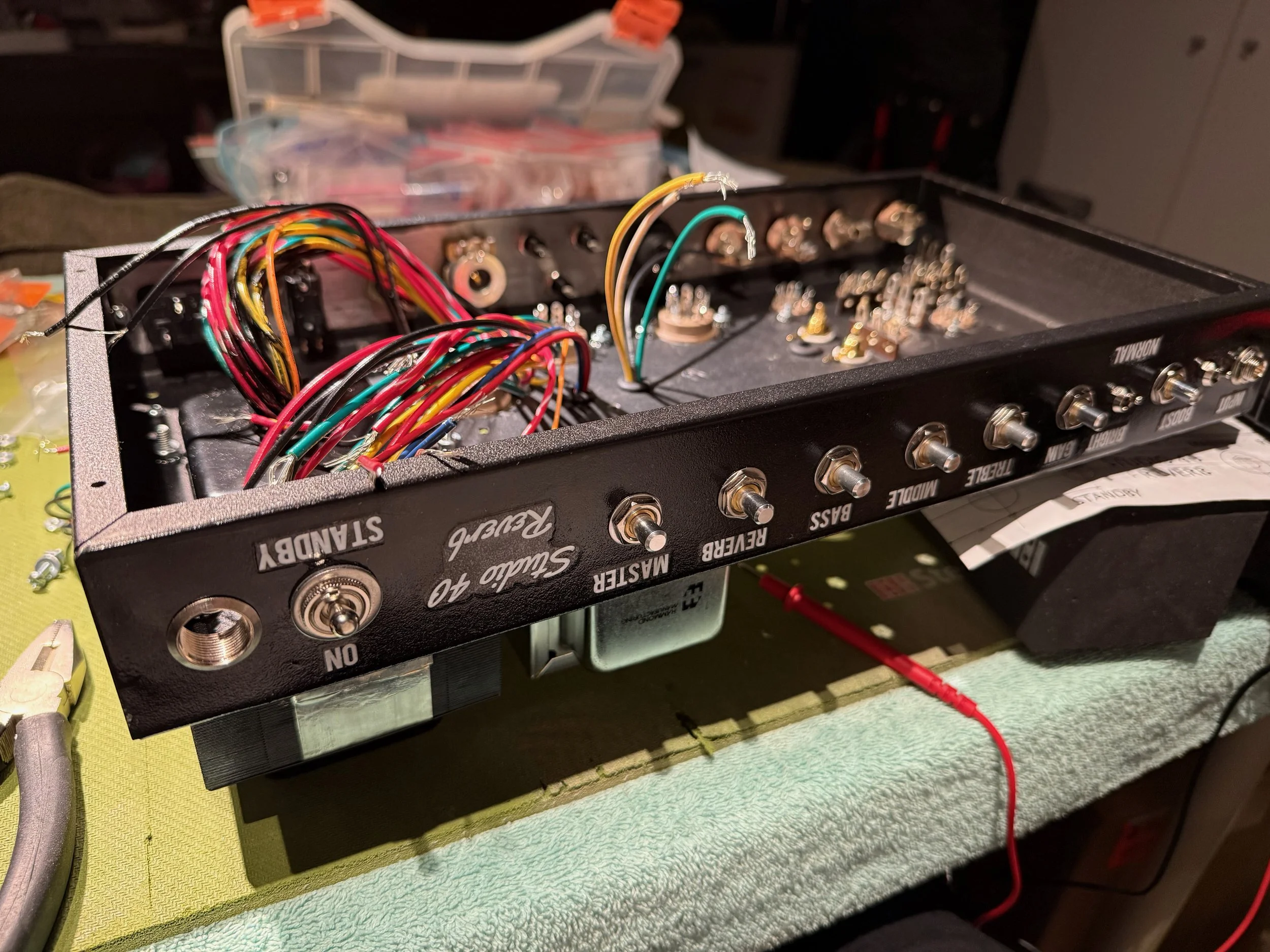 A partially disassembled electronic device with multiple colorful wires, knobs, and jacks, placed on a work surface.