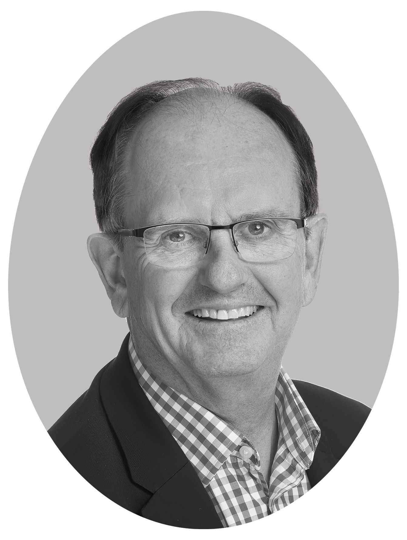 Black and white headshot of a smiling man wearing glasses, a checked shirt, and a dark blazer.