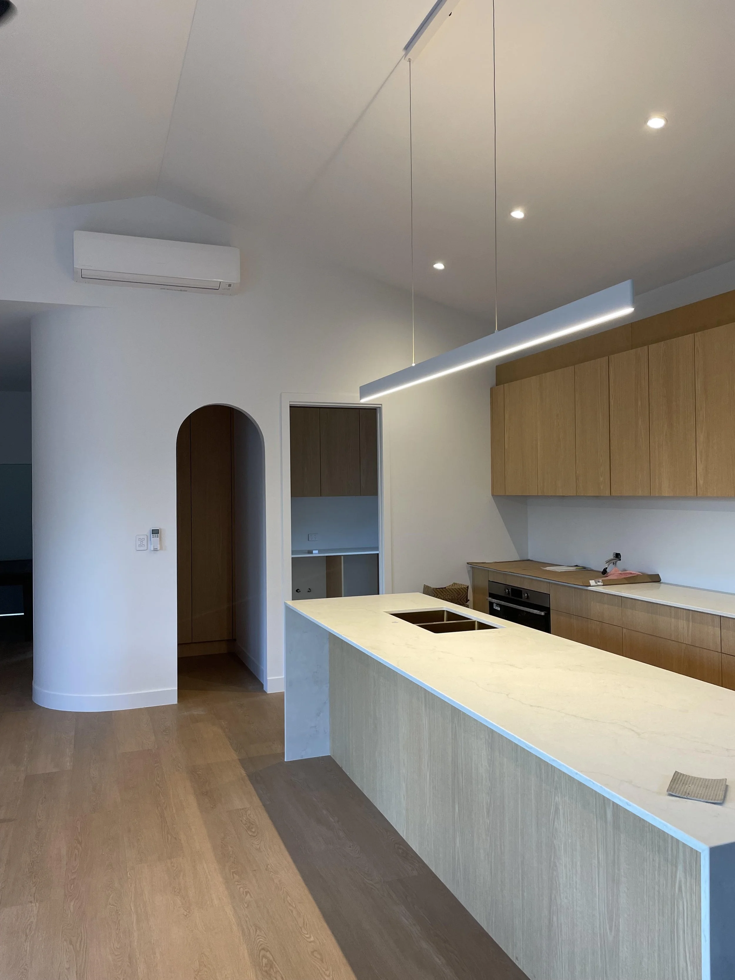 Modern kitchen with white island, wooden cabinets, and recessed lighting.