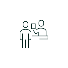 Simple icon of a person standing and another sitting at a desk, representing an interview or consultation.
