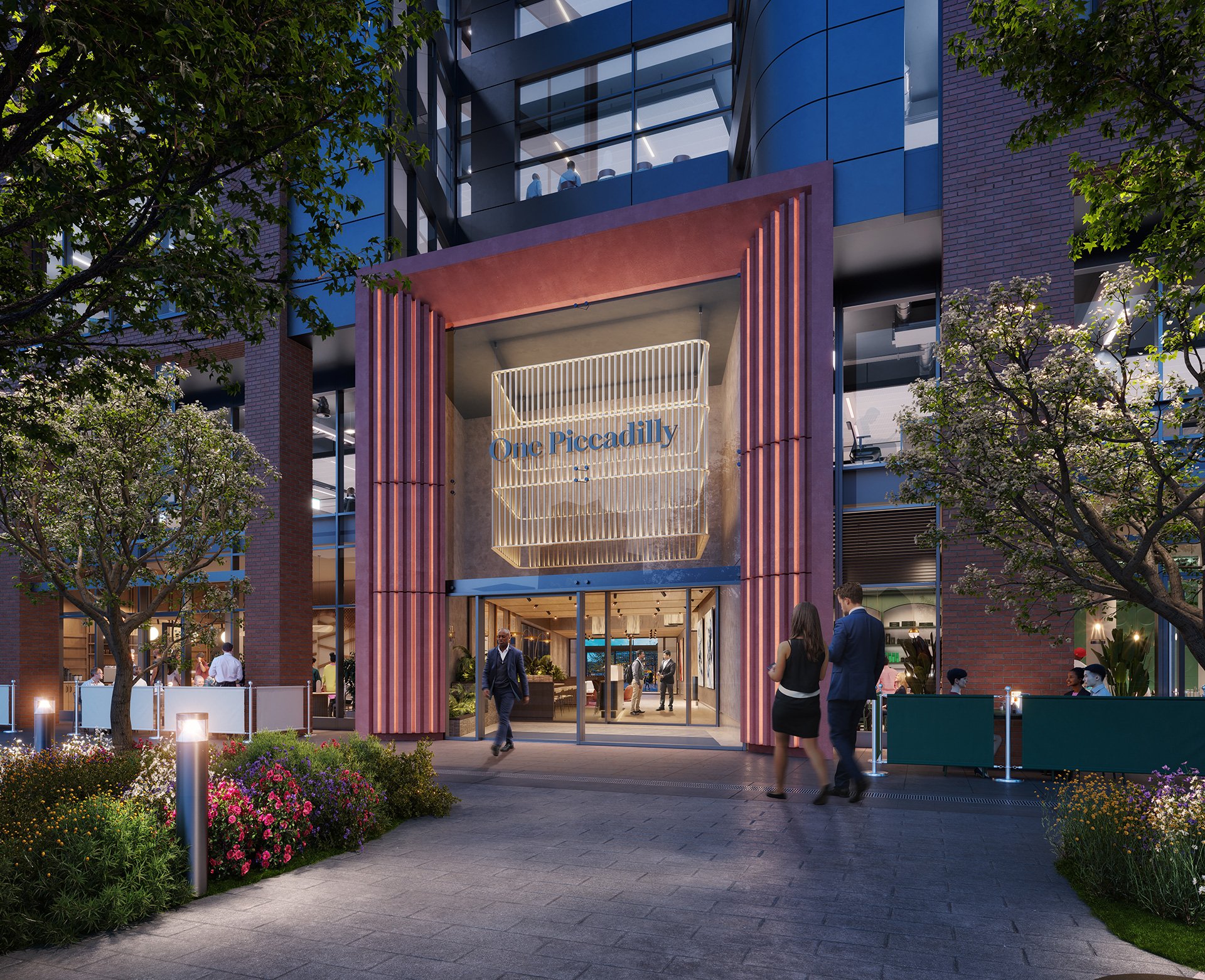 Exterior view of a modern building named 'One Piccadilly' with a glass entrance, surrounded by trees and colorful flowers, and people walking in and out during the evening.