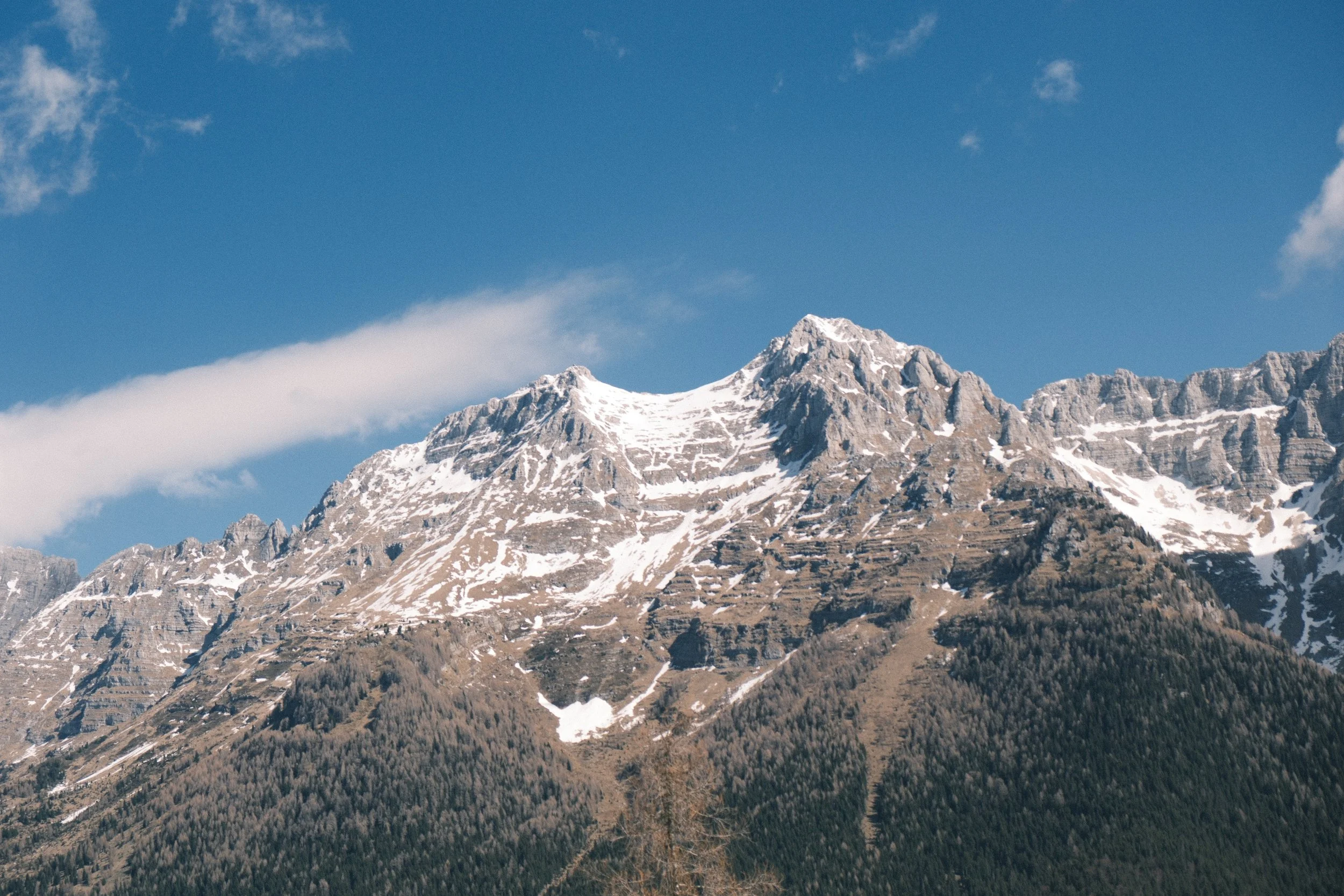 Snow-capped mountain peaks under a bright blue sky with some scattered clouds.