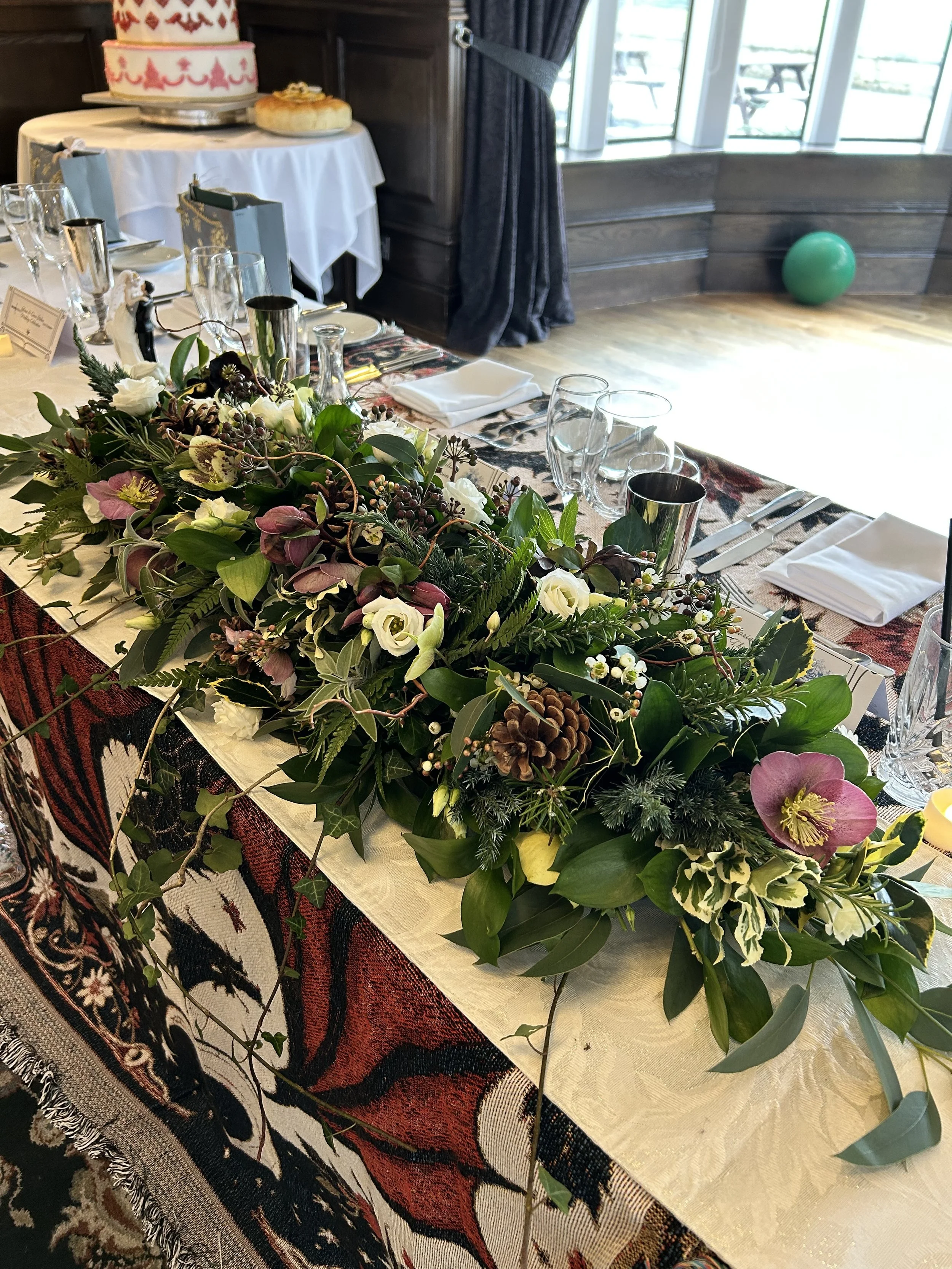 Table decorated with a large floral centerpiece. made by Annie's Flower Shed.