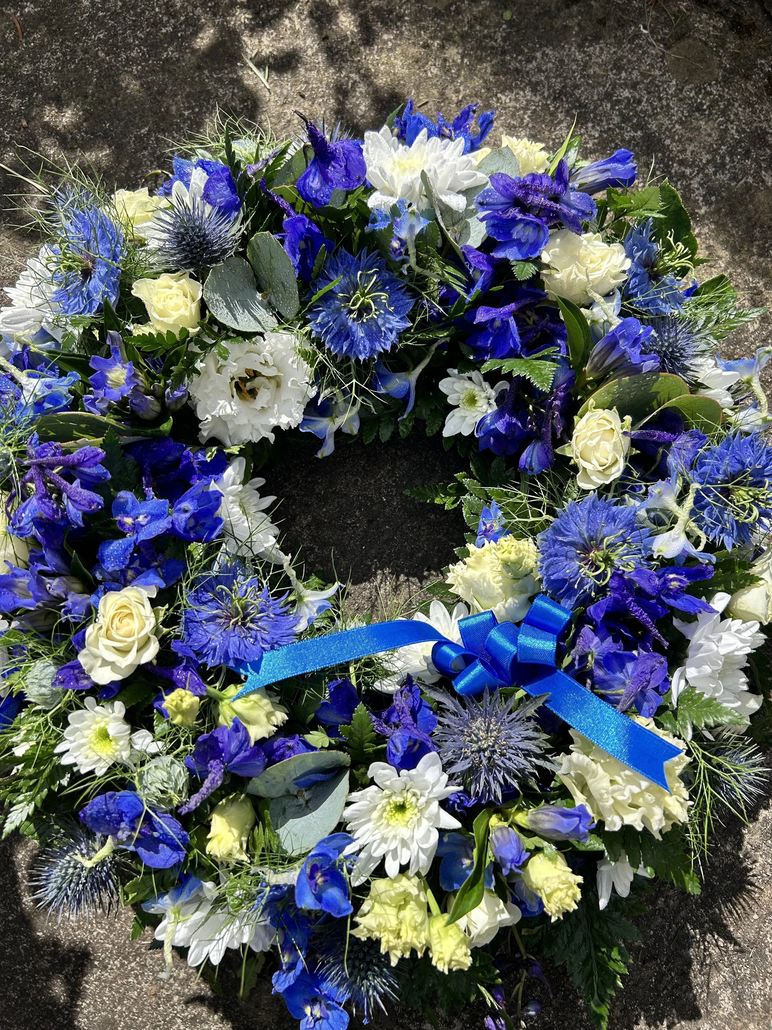 A floral funeral wreath with white and blue