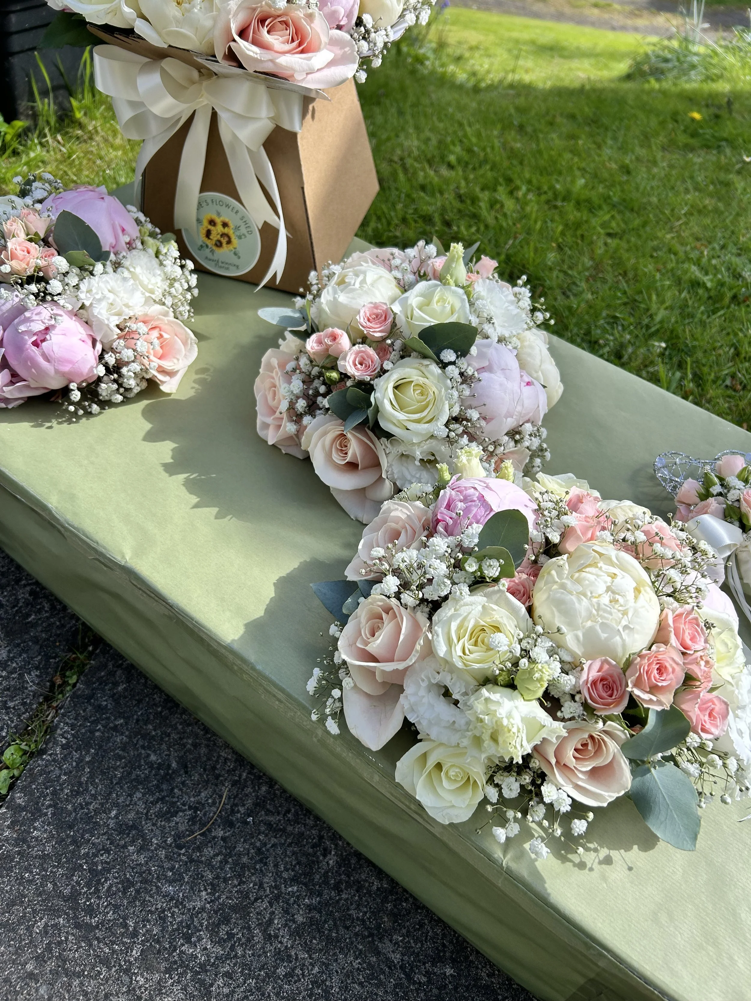 A floral arrangement consisting of white, pink, and cream roses, peonies, and baby's breath.