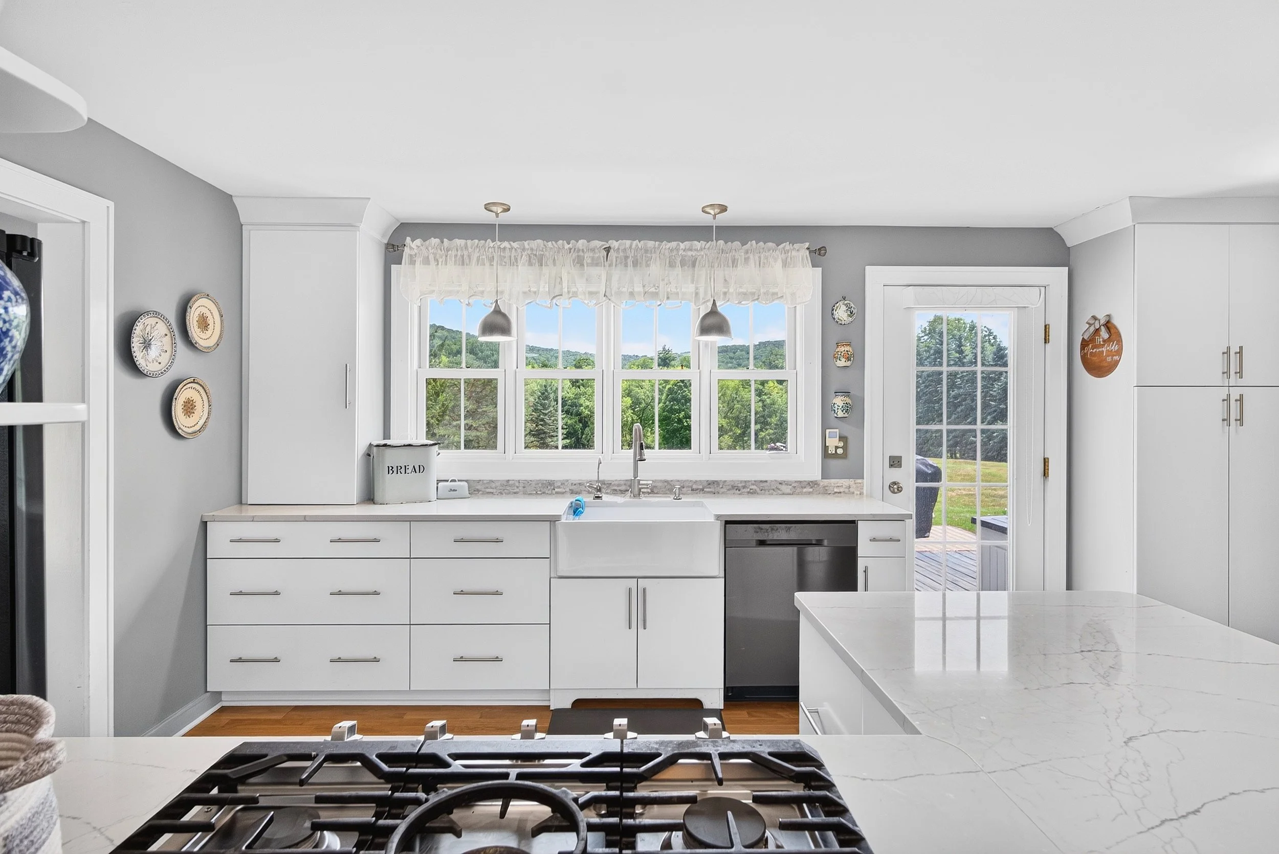 Real estate photography of a bright residential kitchen with white cabinetry, central island and natural light.