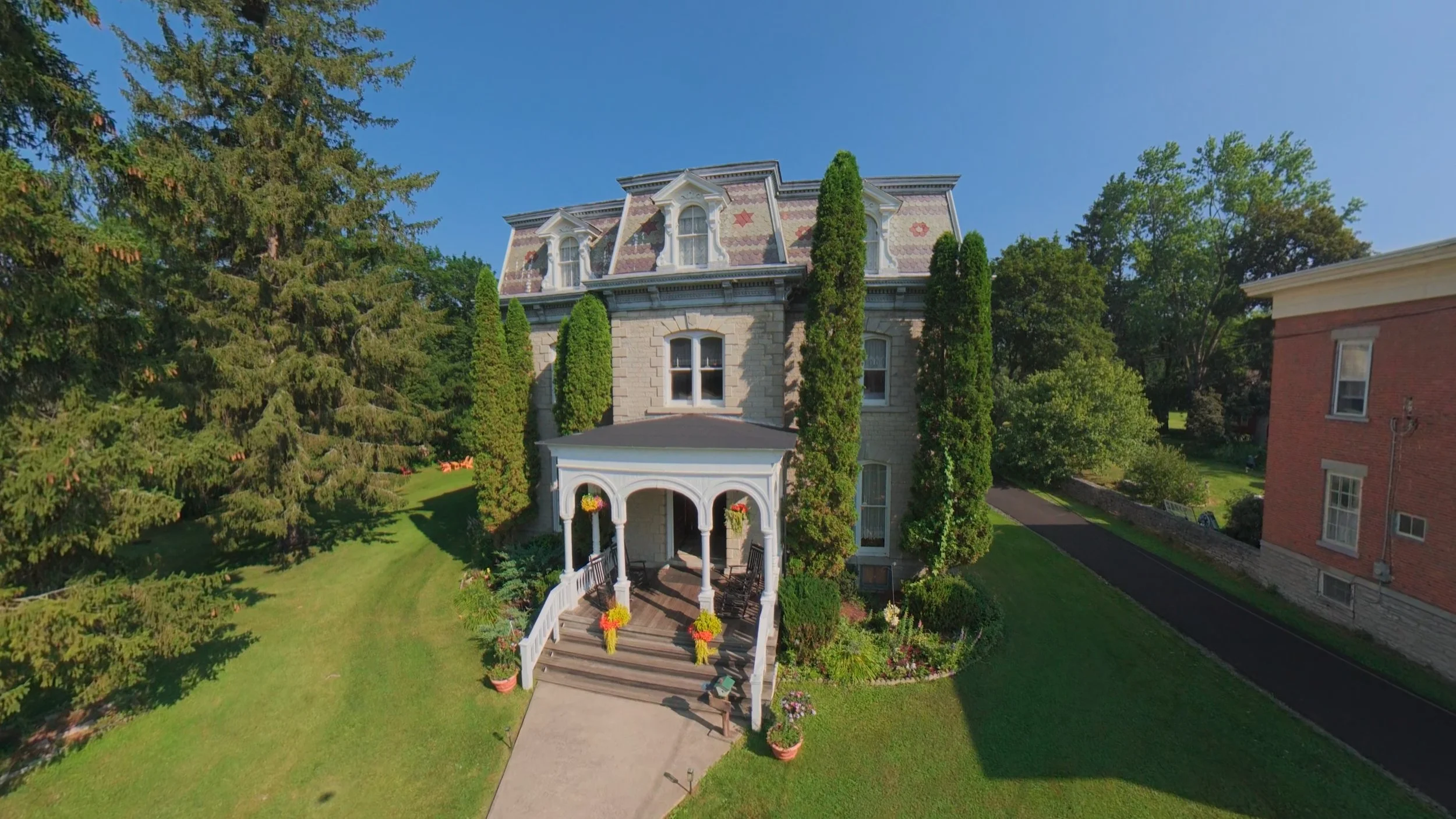 Professional drone photography of a historic stone mansion, showcasing the property's architecture, entrance and surrounding grounds. Aerial real estate photography by Boa Vista Media