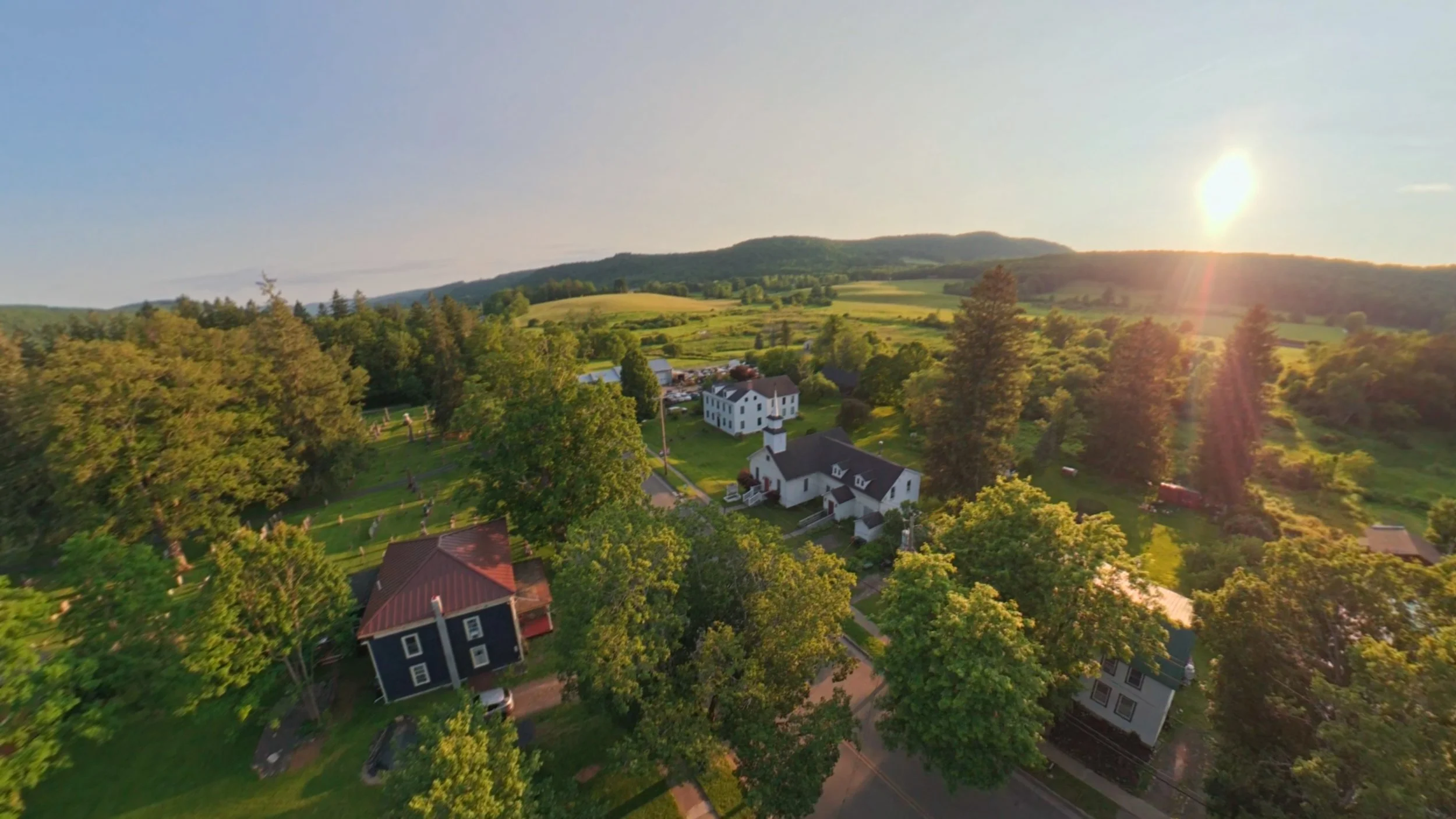 Golden-hour aerial drone photography of residential properties surrounded by Rees and countryside, showcasing the homes and their natural surroundings