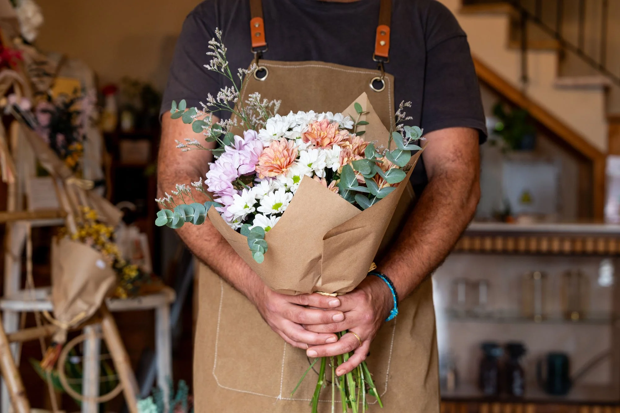 Persona sosteniendo un ramo de flores en una tienda de flores.