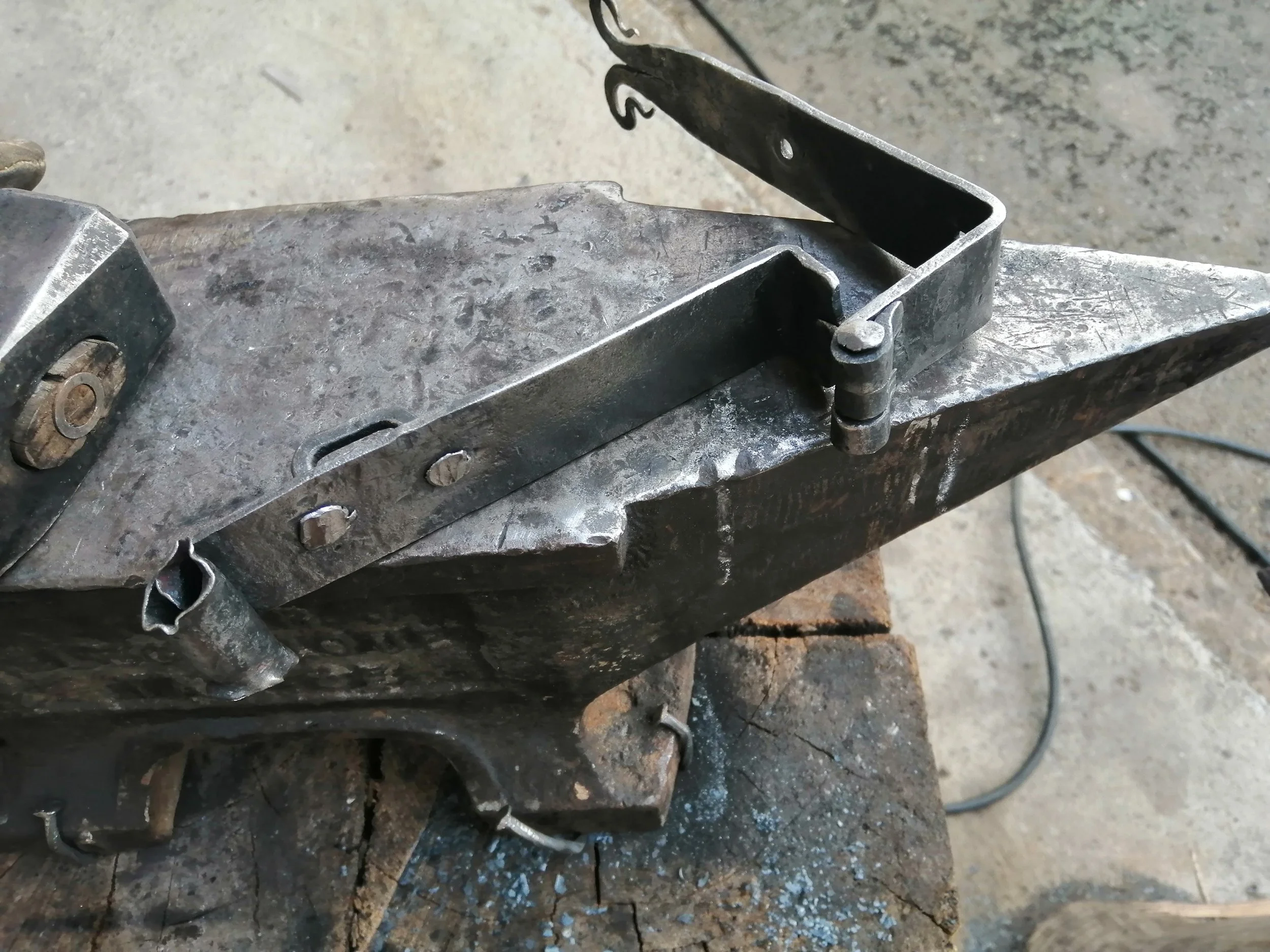 Photo d'une pièce de métal montée sur une surface de travail en métal ou pierre, avec des boulons et une pièce en position levée.