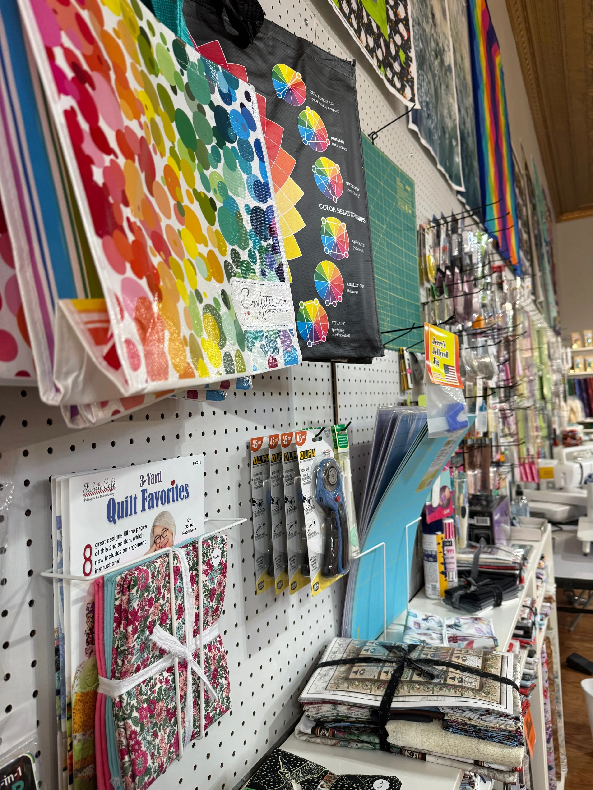 Sewing and quilting supplies on a store shelf, including fabric, thread, and quilting books.