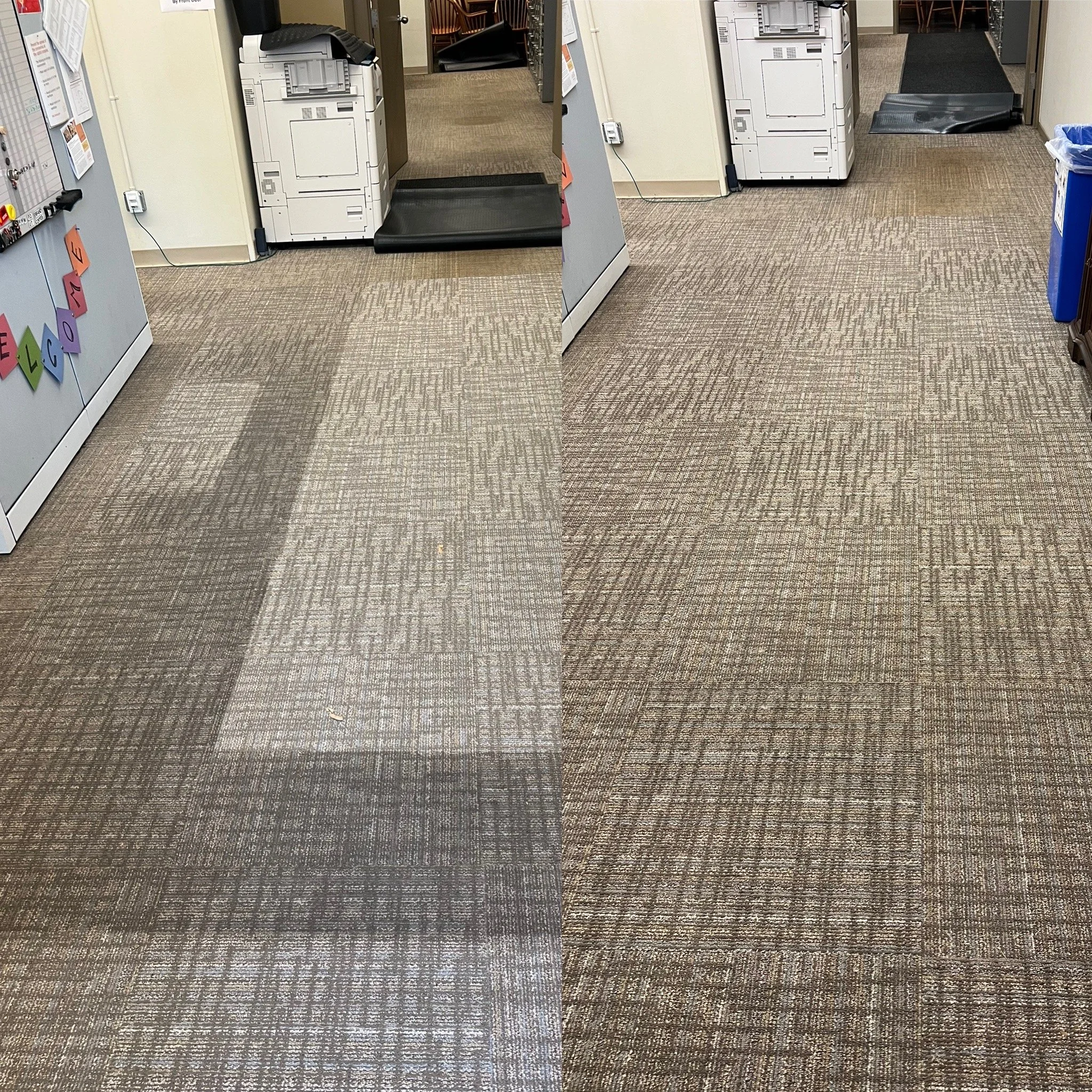 Photo of an indoor office or business setting with carpeted floor, gray cabinets, a copier or printer, and a trash bin, with some chairs visible through an open door in the background.