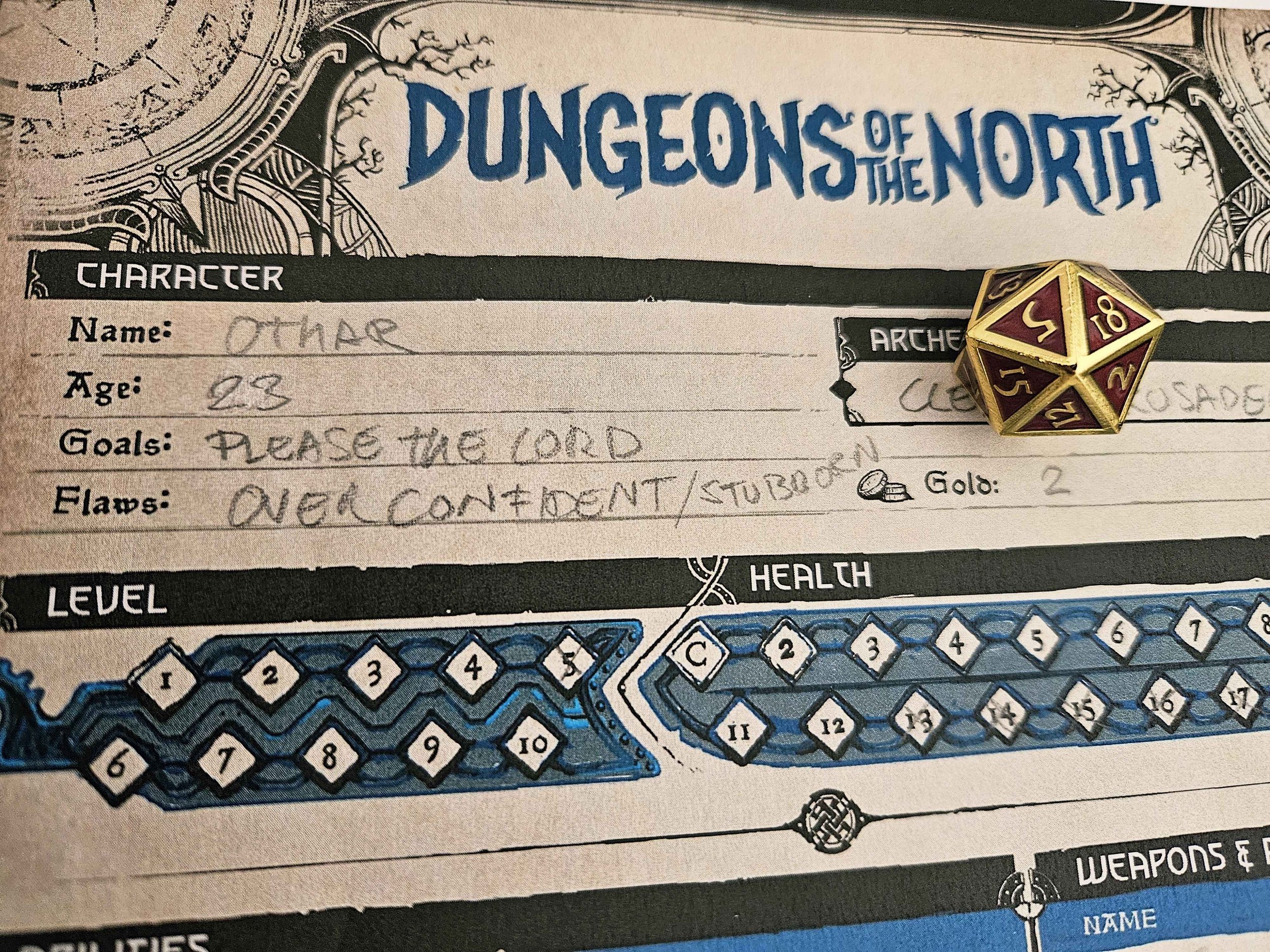 Close-up of a character sheet for a game called Dungeons of the North, showing sections for character name, age, goals, flaws, and stats with a decorative border. There is a 20-sided die (d20) with red, gold, and cream colors placed on the sheet.