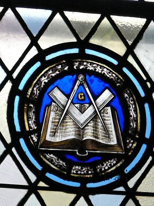Stained-glass window bearing the square and compasses.