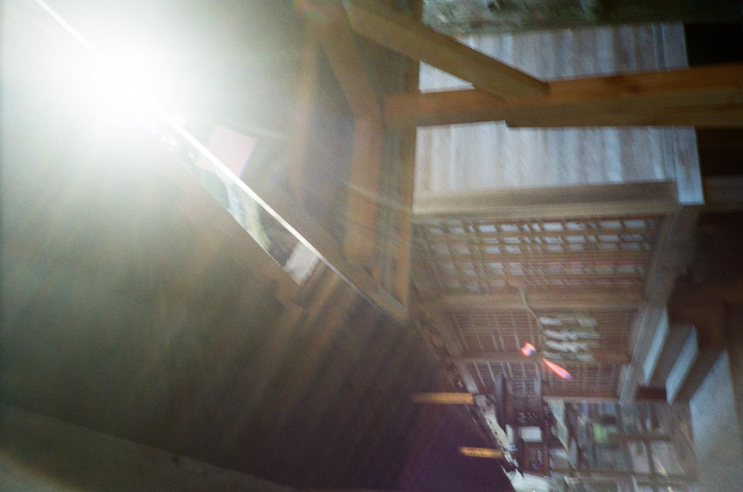 Image of several wooden crates stacked on a table or flat surface, with sunlight shining onto the crates, creating lens flare and overexposure on the left side of the image.