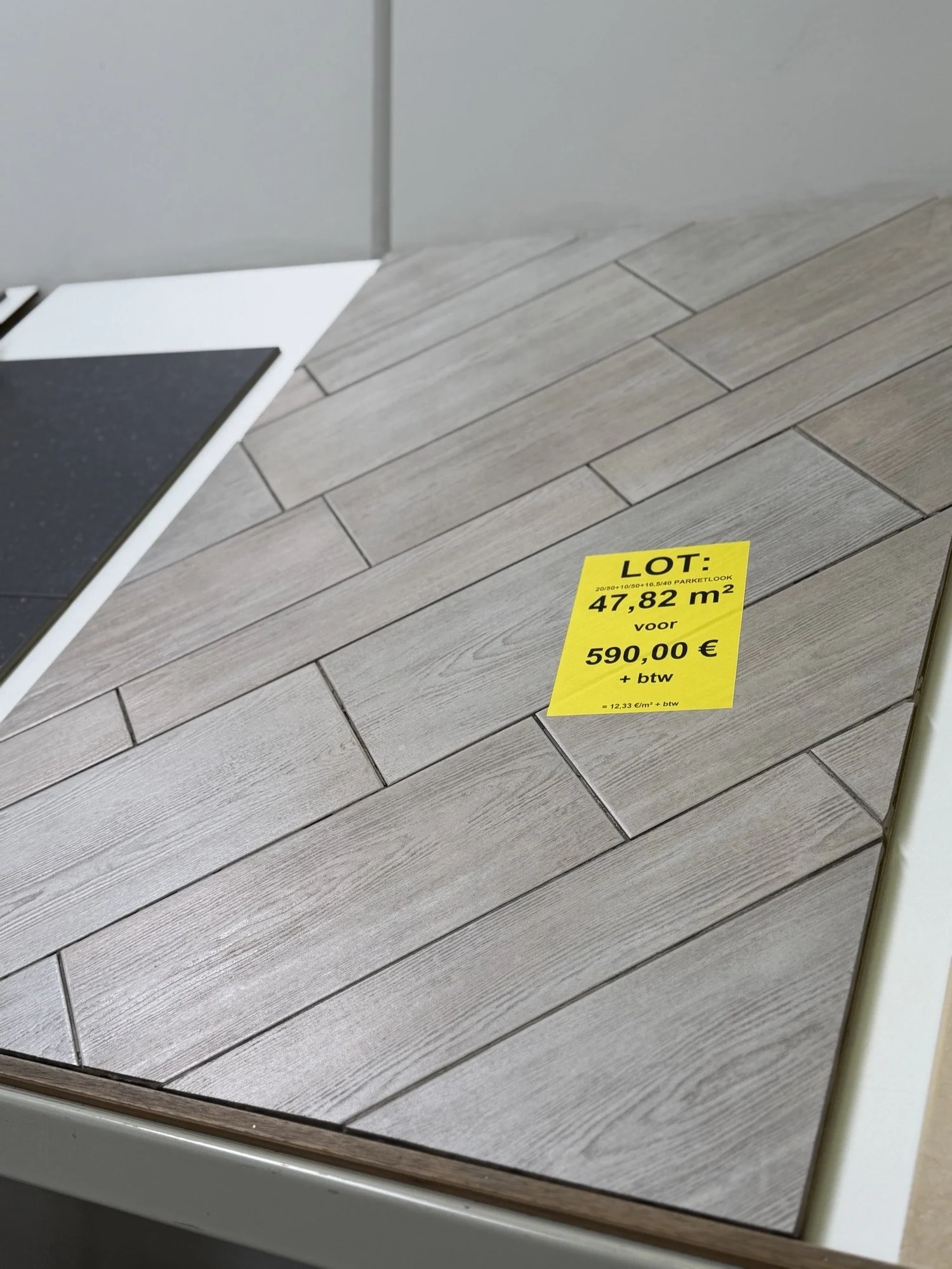 Laminaat vloer met een geel prijskaartje daarop geschreven: LOT: 47,82 m² voor 590,00 € plus BTW.