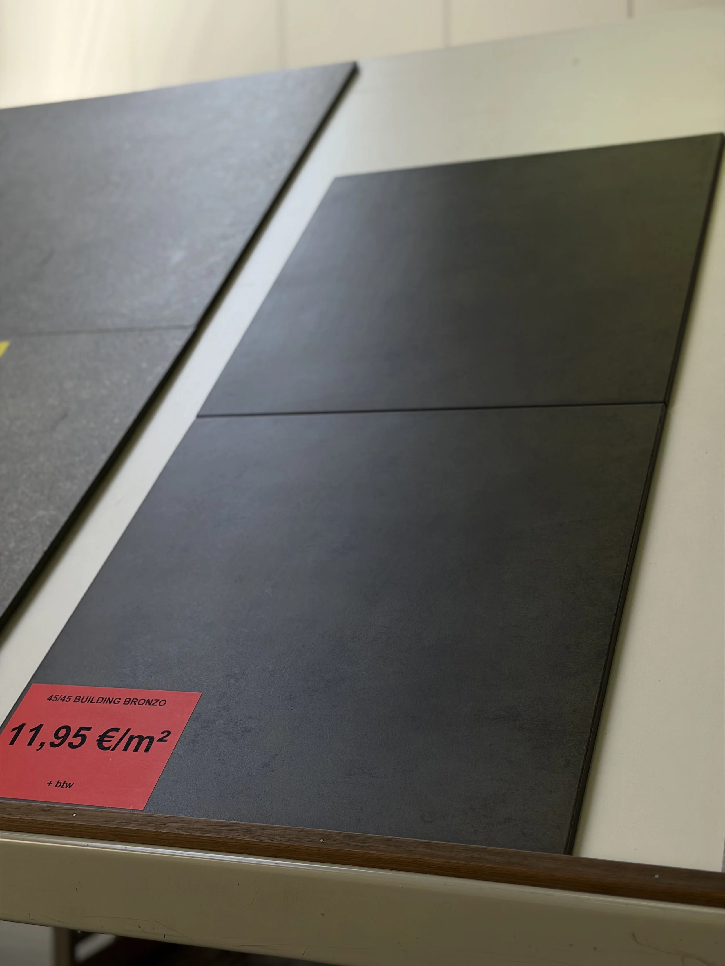 Tegelstaal in de winkel met prijskaartje dat 11,95 euro per vierkante meter kost.