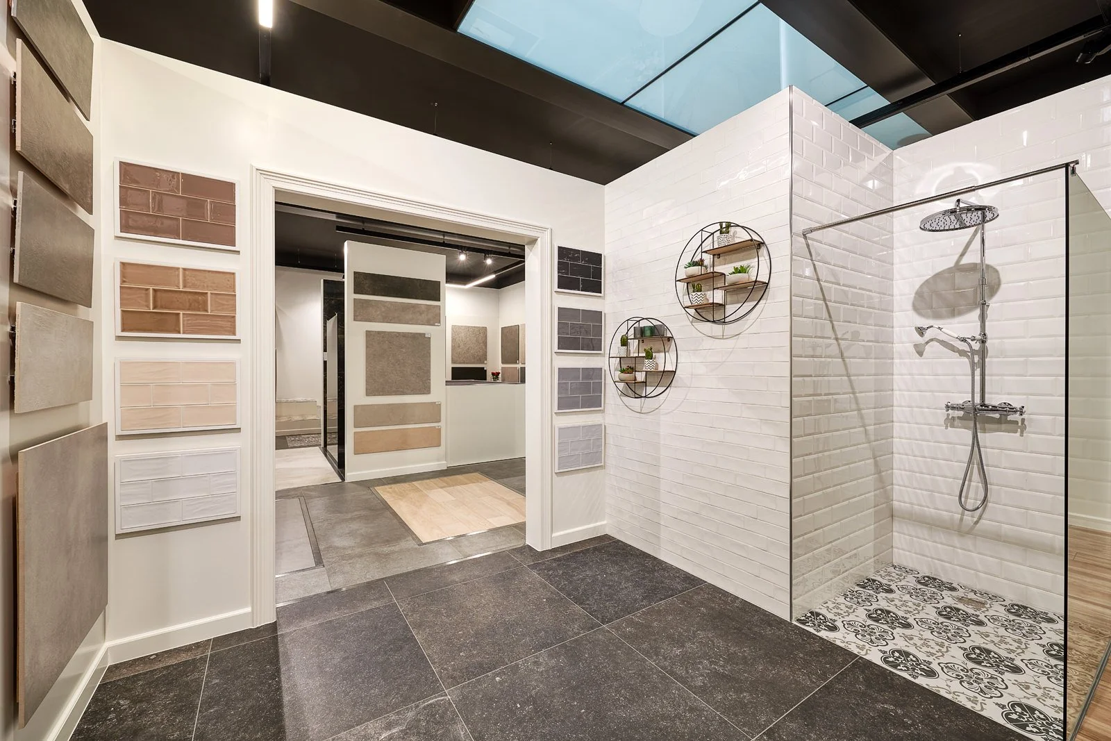Binnenkijker in een showroom met wandtegels en een open badkamer met een inloopdouche.