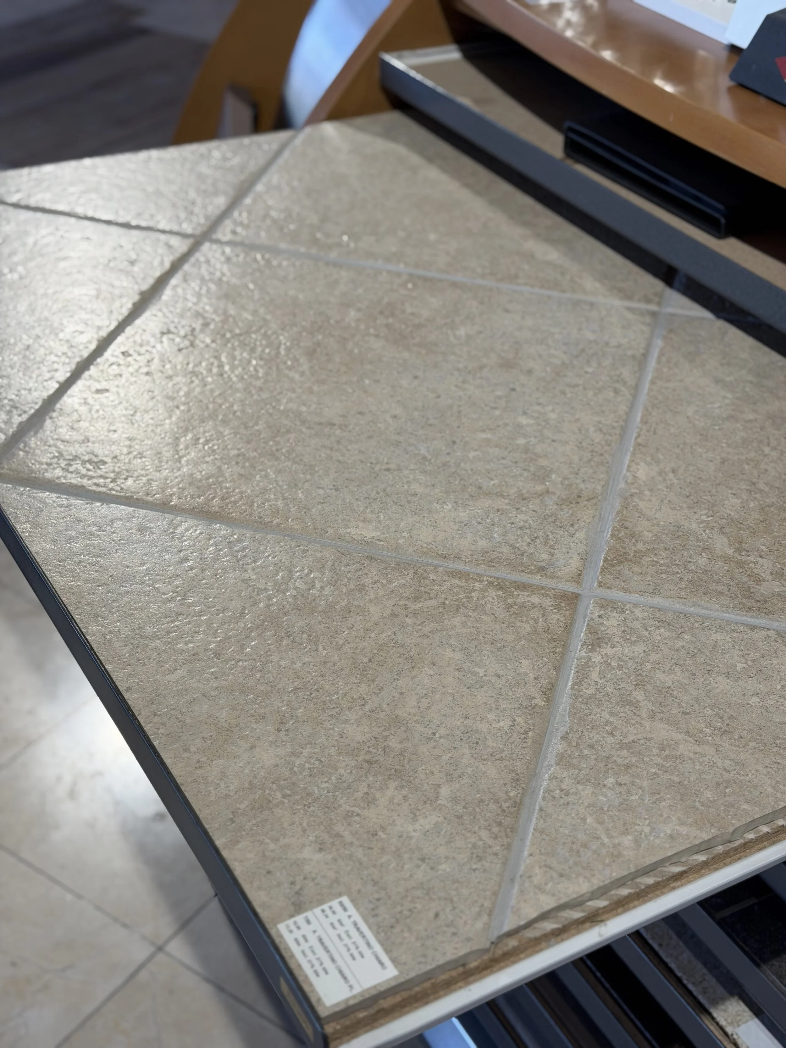 Tegelstaaltable met verschillende soorten stenen en tegels in een winkel of showroom.